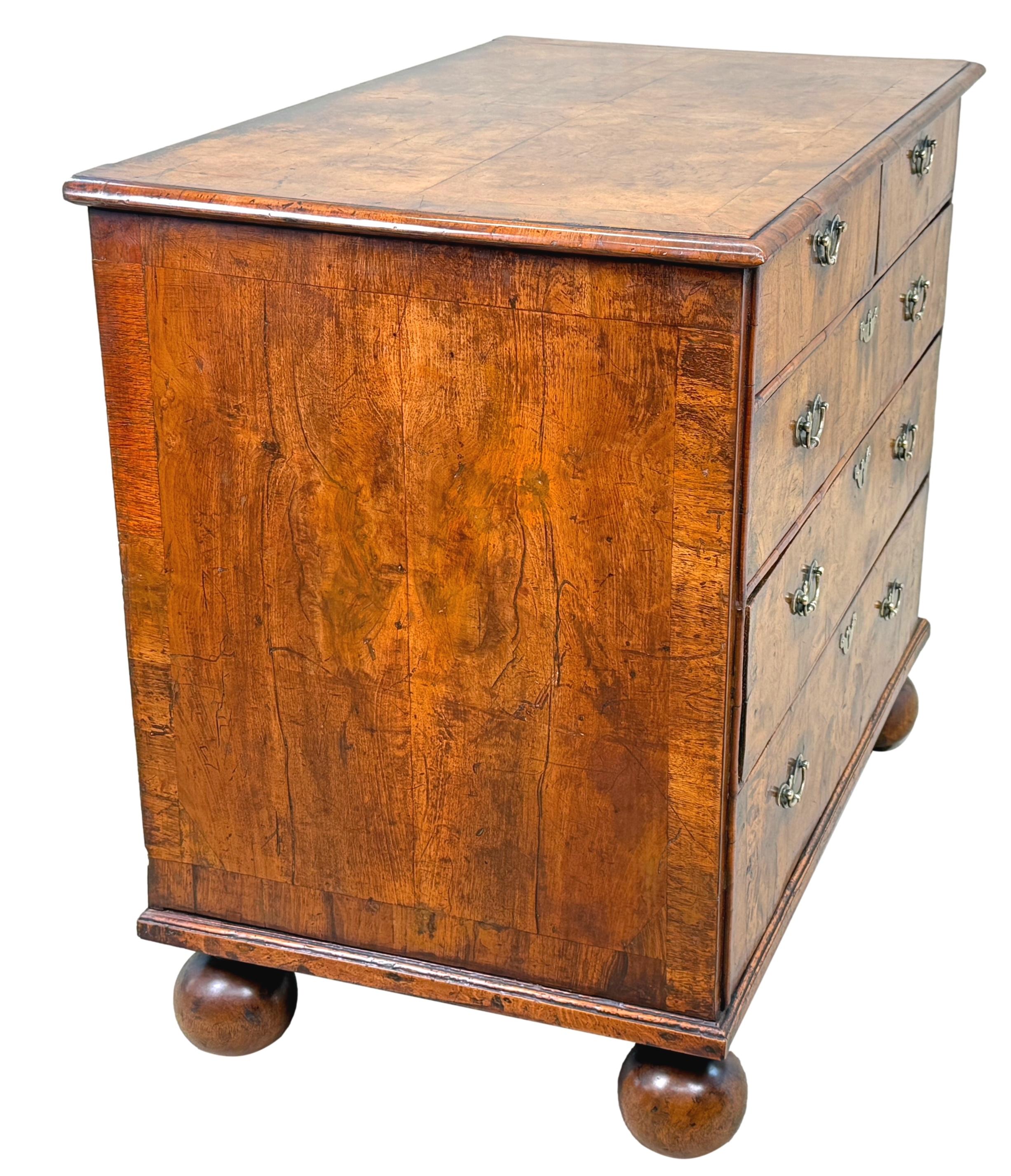 Cassettone in legno di noce del periodo Queen Anne, molto attraente, con piano impiallacciato a quarti ben figurato con decorazioni a fasce incrociate, due cassetti corti e tre cassetti lunghi con inserti in ottone di ricambio, fiancheggiati da