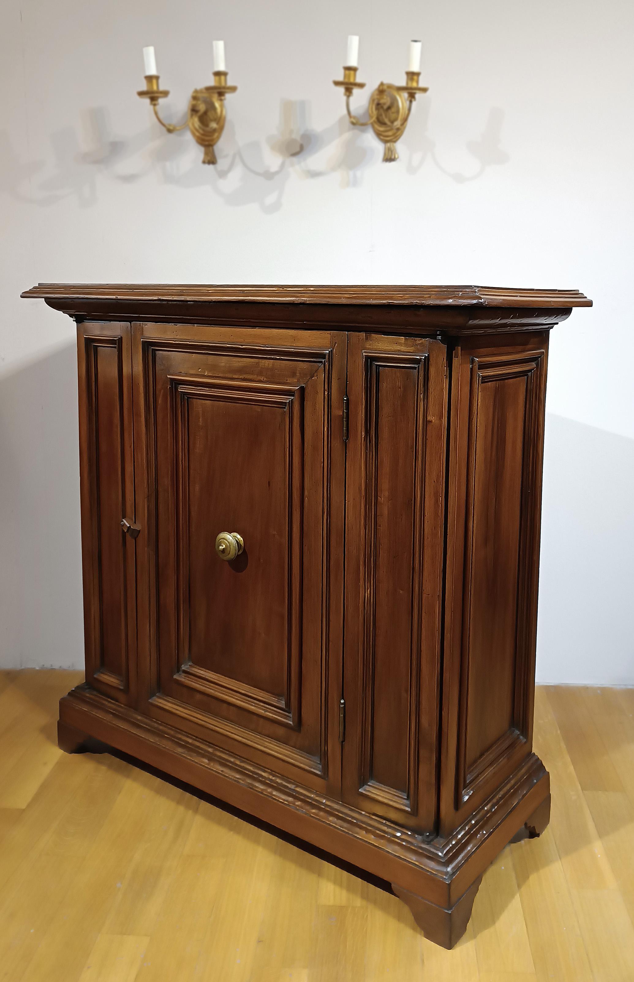 Elegantes kleines Sideboard aus massivem Nussbaumholz, fein von Hand geschnitzt. Die Anrichte verfügt über Konsolenfüße, eine Massivholzplatte und ist mit geometrischen, rautenförmigen Schnitzereien auf der Vorderseite und an den Seiten verziert,