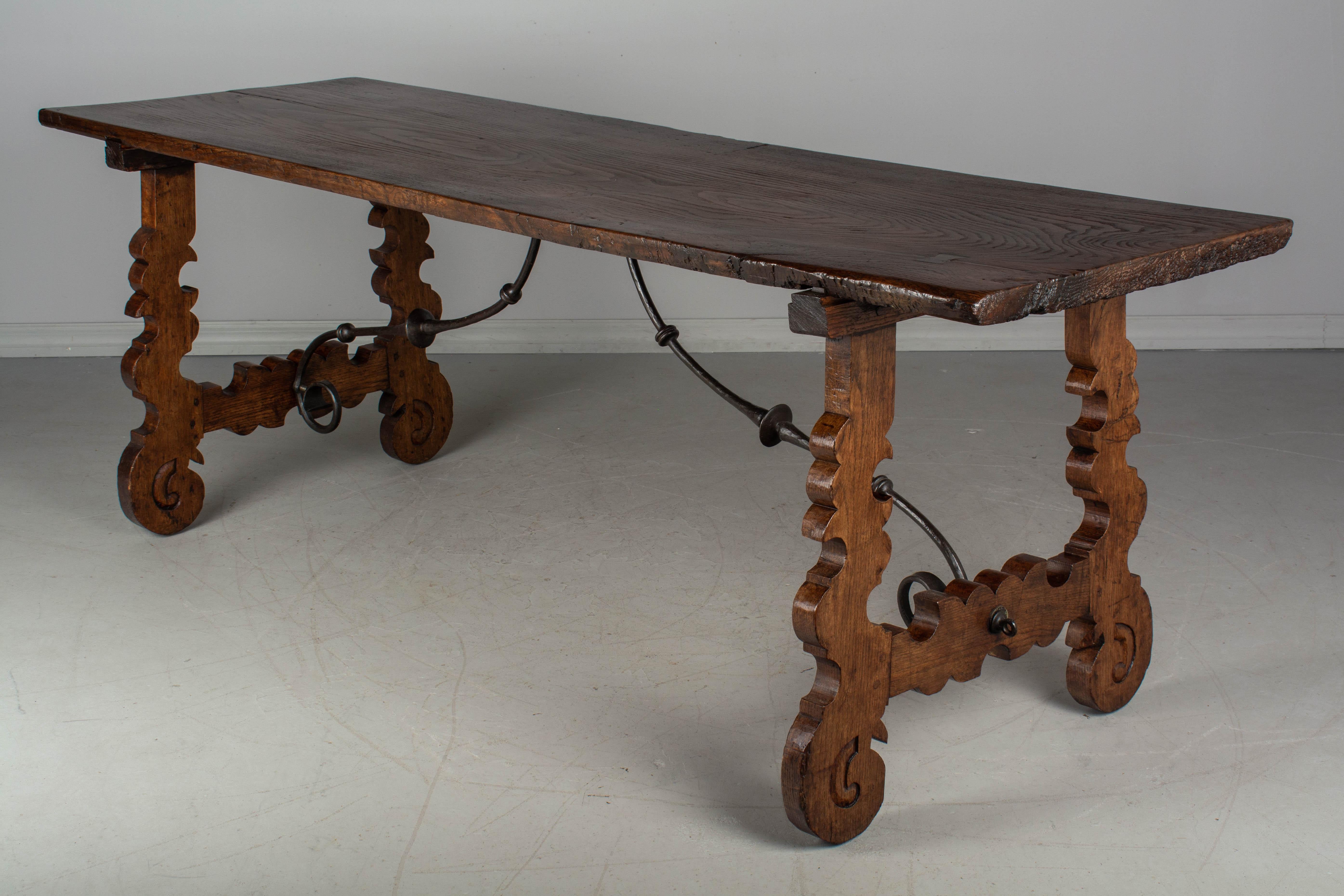 An 18th century Spanish Baroque refectory table made of solid chestnut with lyre shaped legs joined by wrought iron stretchers. The top is made from a single 1-3/4