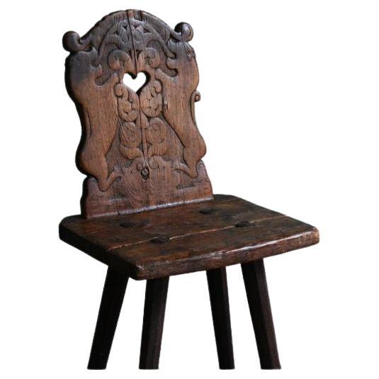 A Swiss pine back stool with an open heart carving on the back panel. 

Swiss, early 18th century

Dimensions: H 85 x W 40 x D 34.5 cm.