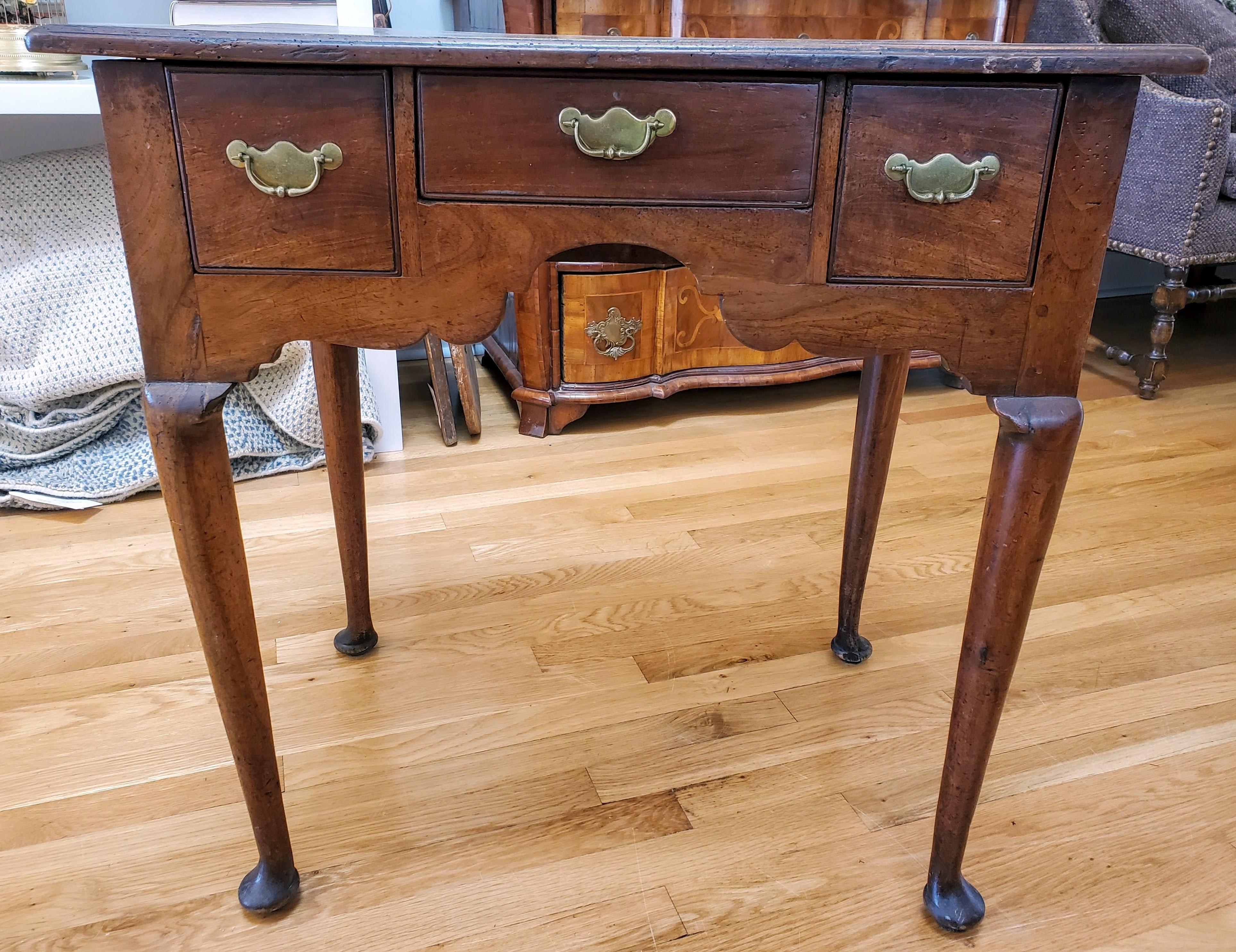 Early 18th century George I walnut lowboy table with three drawers and cabriole legs
Made of highly figured and richly patinated walnut with three drawers retaining the original brass hardware and shaped brackets to cabriole legs with pad feet.