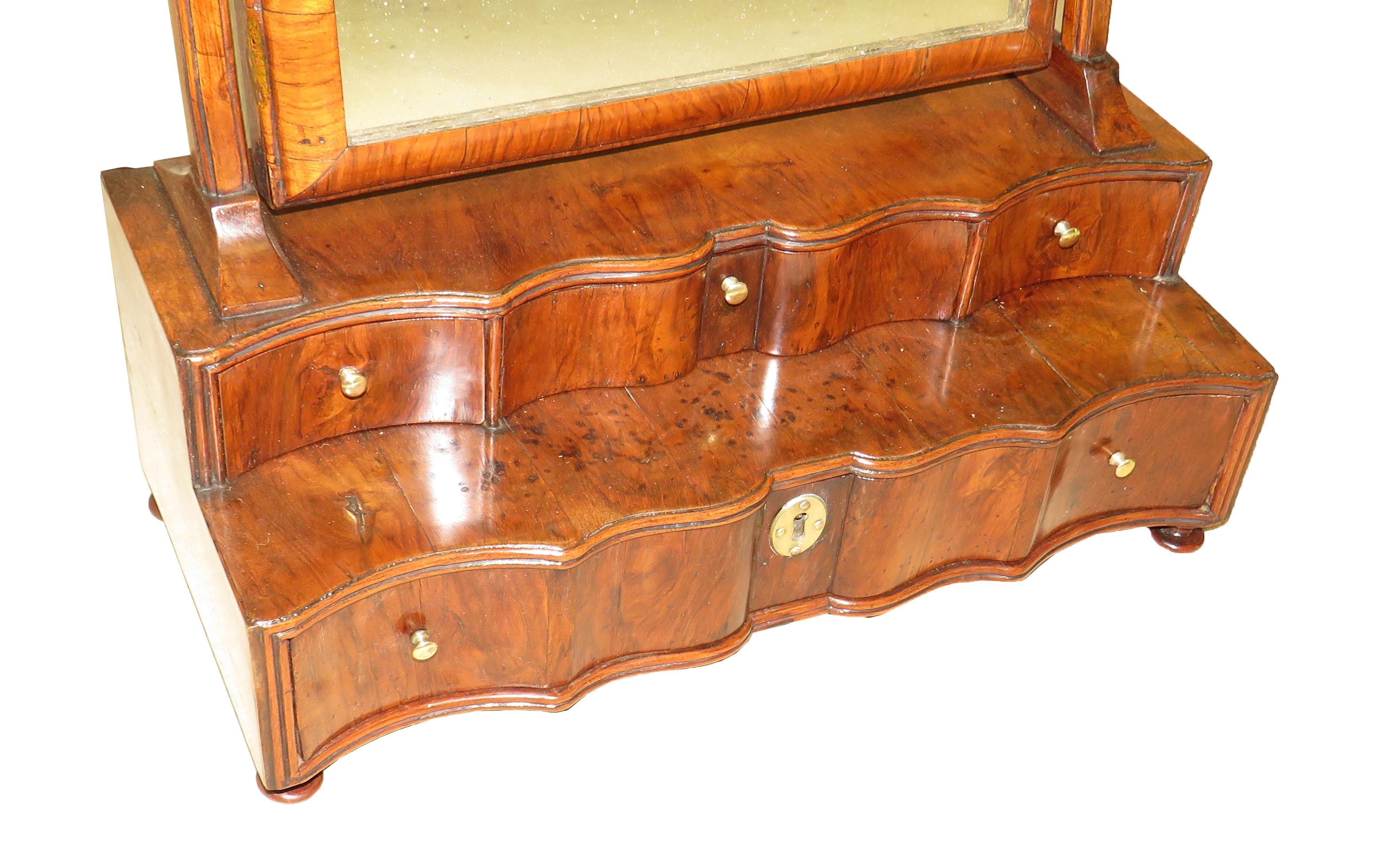 A very good quality early 18th century queen
Anne period walnut dressing table mirror having
Replacement old mirror plate to moulded and shaped
Swing frame over three short and one long drawer
Raised on later turned feet

(Dressing table