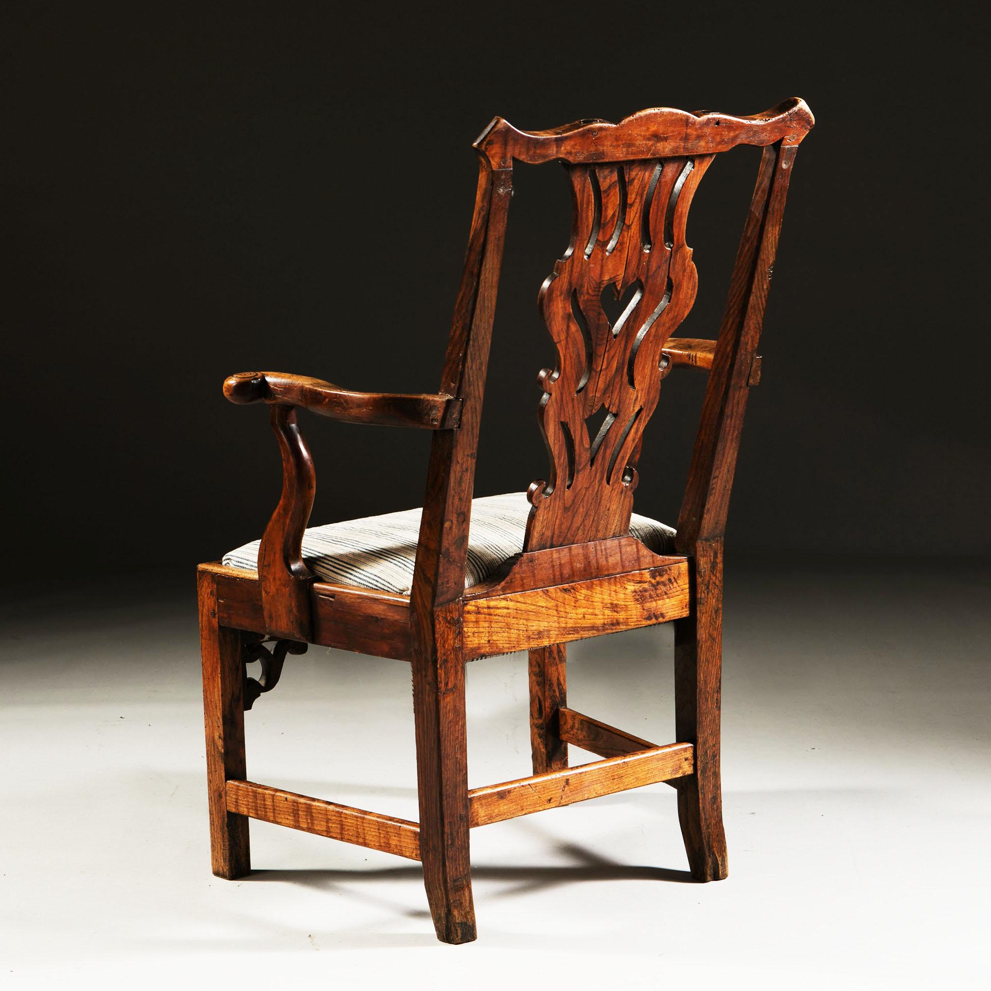A fine early 18th century English yew wood Windsor chair with outswept arms, Chippendale back splat and a carved and shaped apron, with finely figured wood throughout, the drop in seat upholstered in a antique linen stripe.

Height               