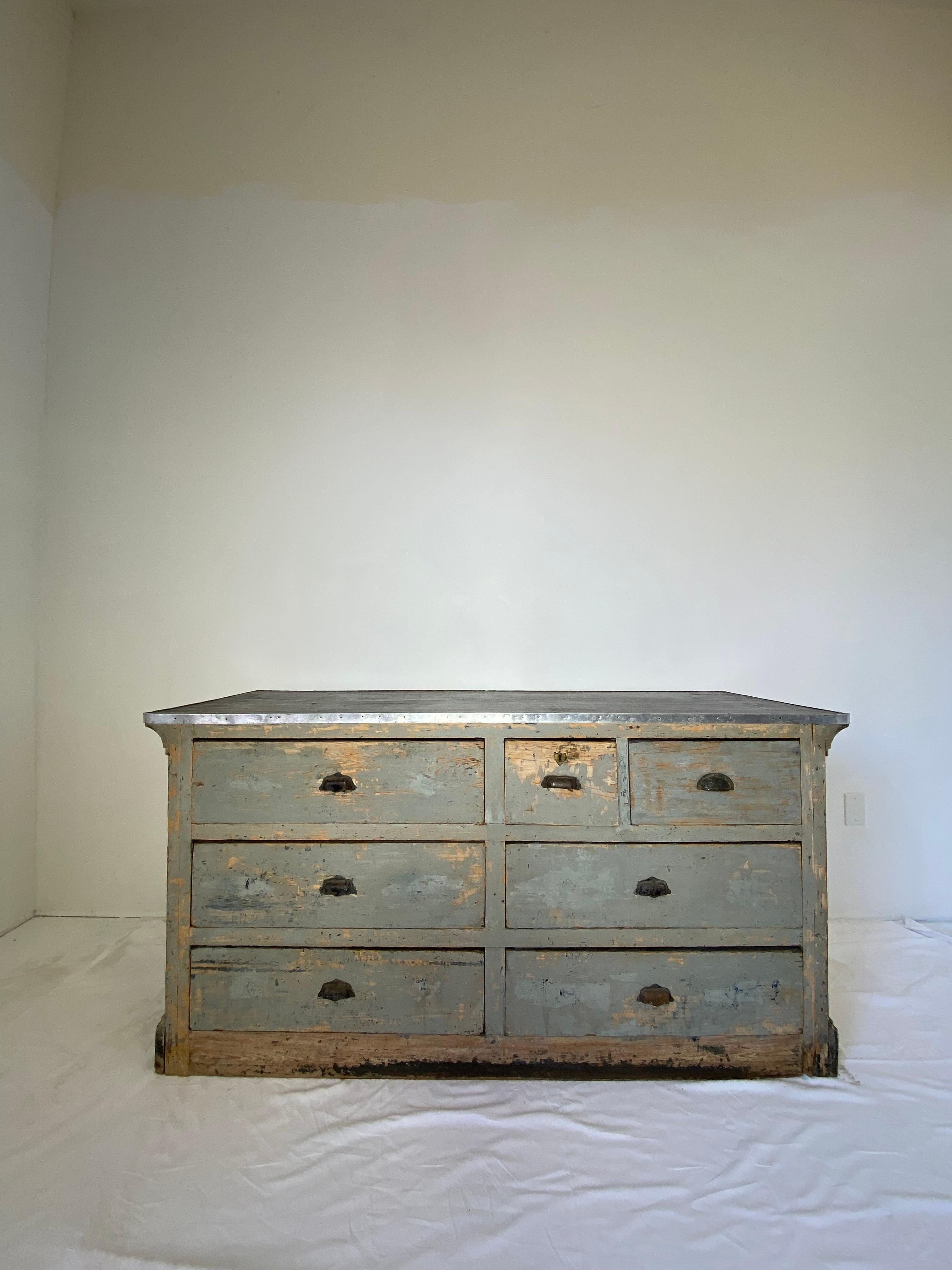 Early 19th century light blue painted store counter with 7 drawers, one drawer with shield emblem key plate iron pull handles (probably added later). Metal border to top of counter new.