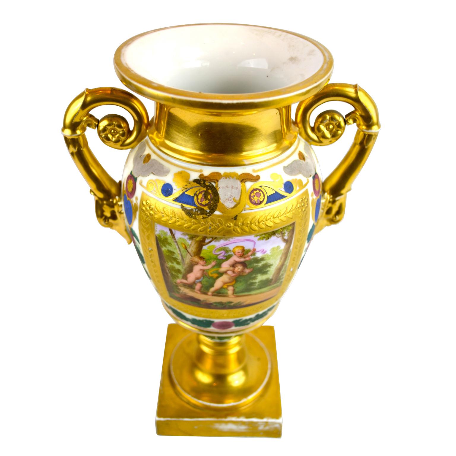 A Paris porcelain urn with swan’s head handles; beautifully painted frolicking cupids to the front, and matte and burnished framed musical motifs to the back. Some rubbing consistent with age.
