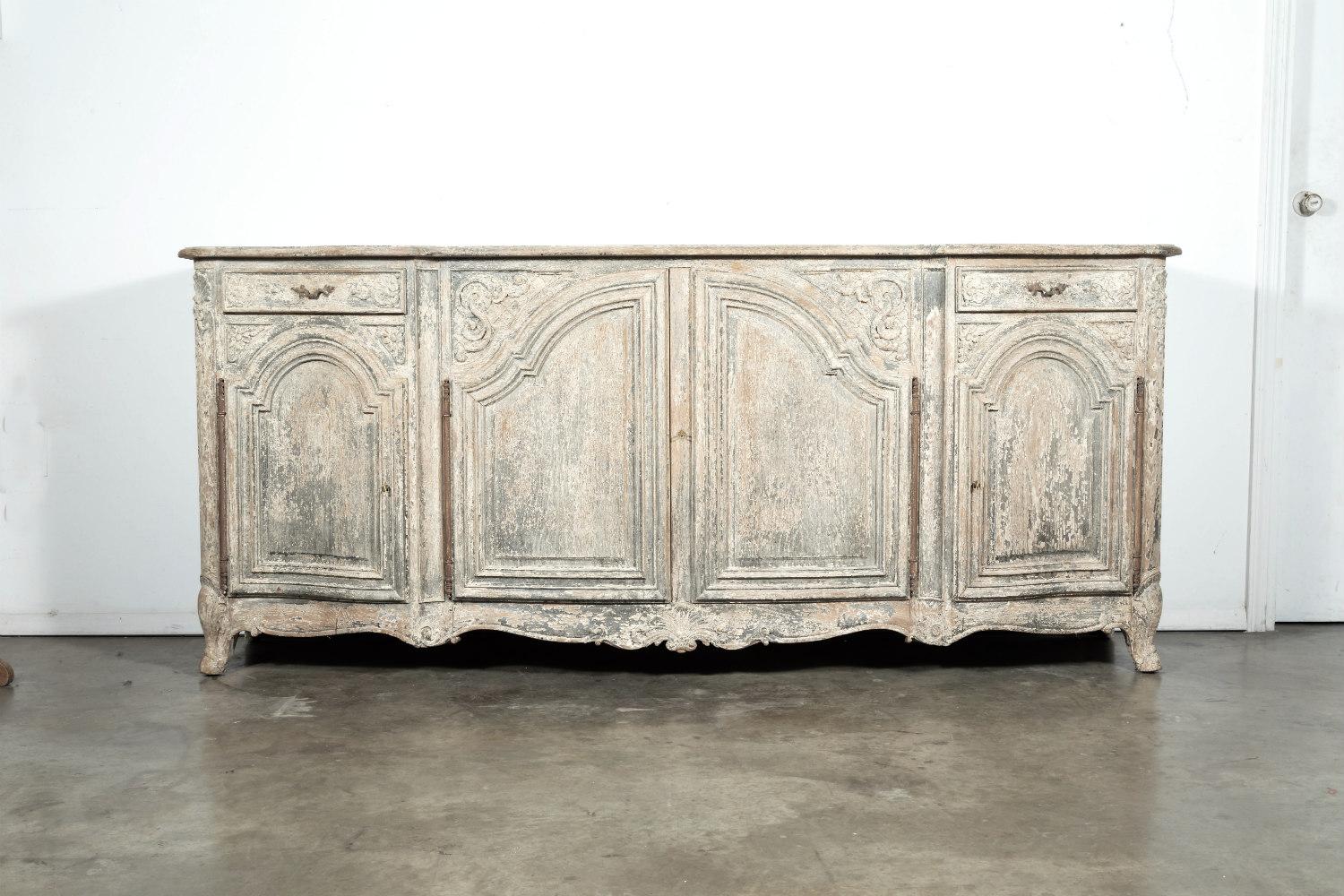 A wonderful, large Louis XV style painted oak enfilade buffet, circa early 1900s, having a moulded serpentine top over two large cabinet doors flanked by two small drawers above two smaller cabinet doors, all opening to reveal a center shelf.