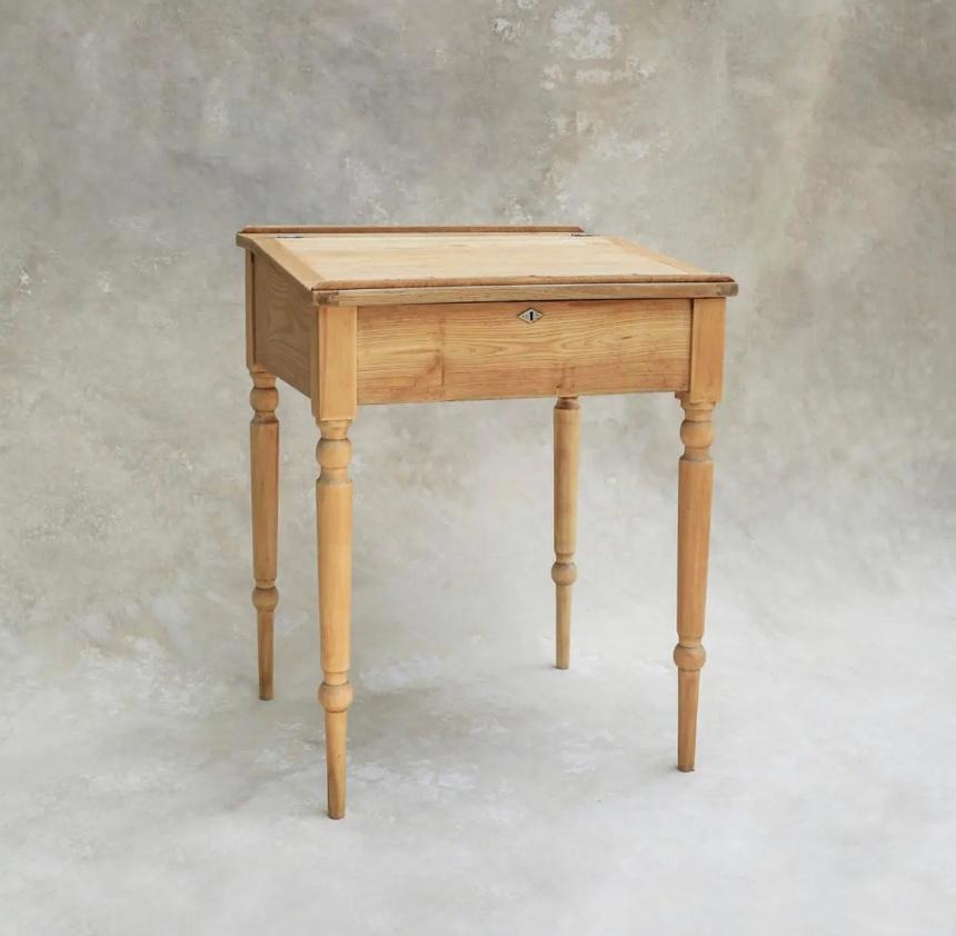Vintage Swedish pine writing desk from the early 1900s, meticulously sanded and bleached to unveil its inherent natural color and wood grain. The slanted lift-top lid gracefully hinges open, unveiling a generously sized open well, adding