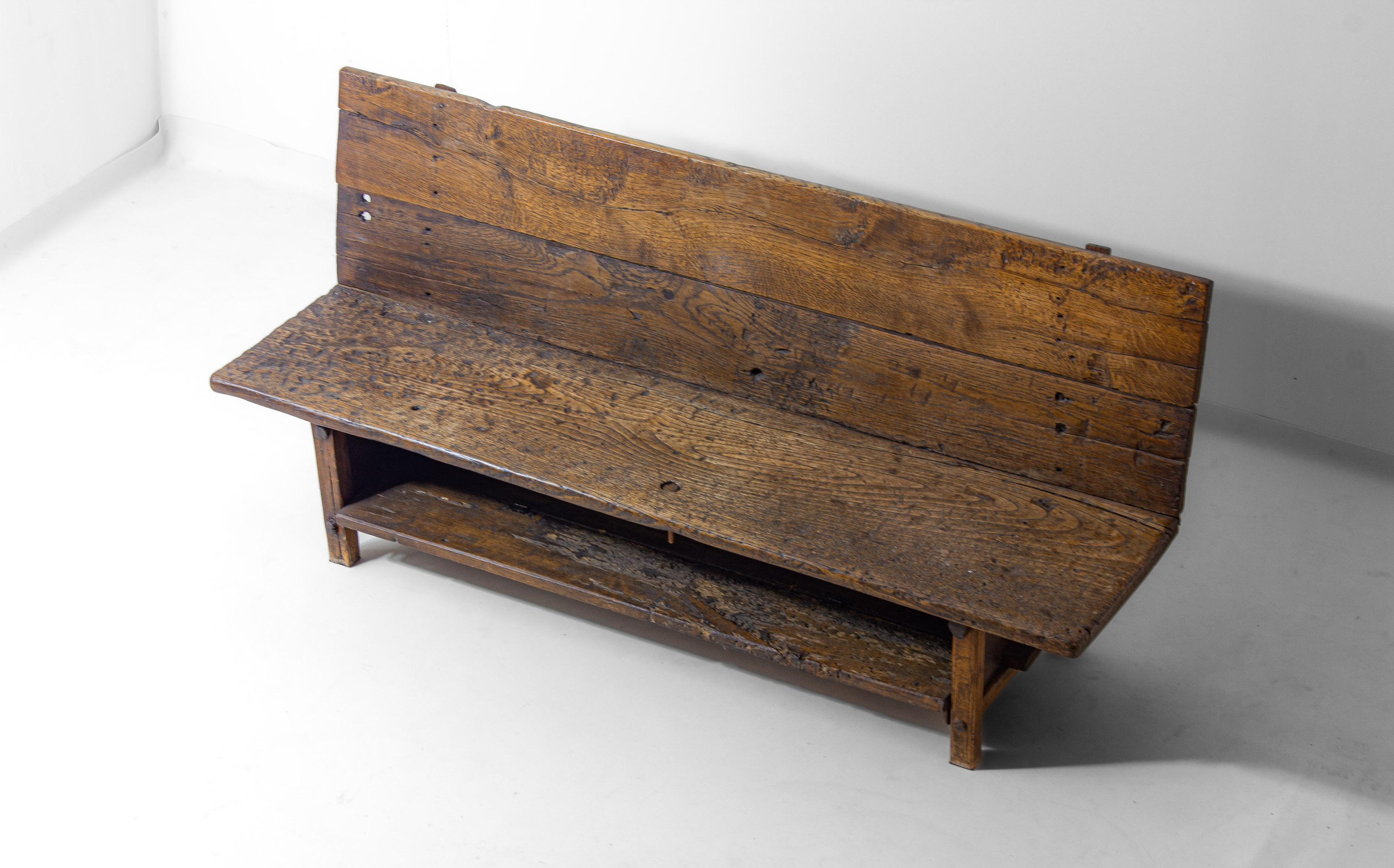 Ce banc rustique de fermette française du début des années 1900 est une véritable pièce de mobilier Art Populaire. Construit en bois massif, il présente une forte usure, de l'âge et une belle patine qui mettent en évidence sa longue histoire