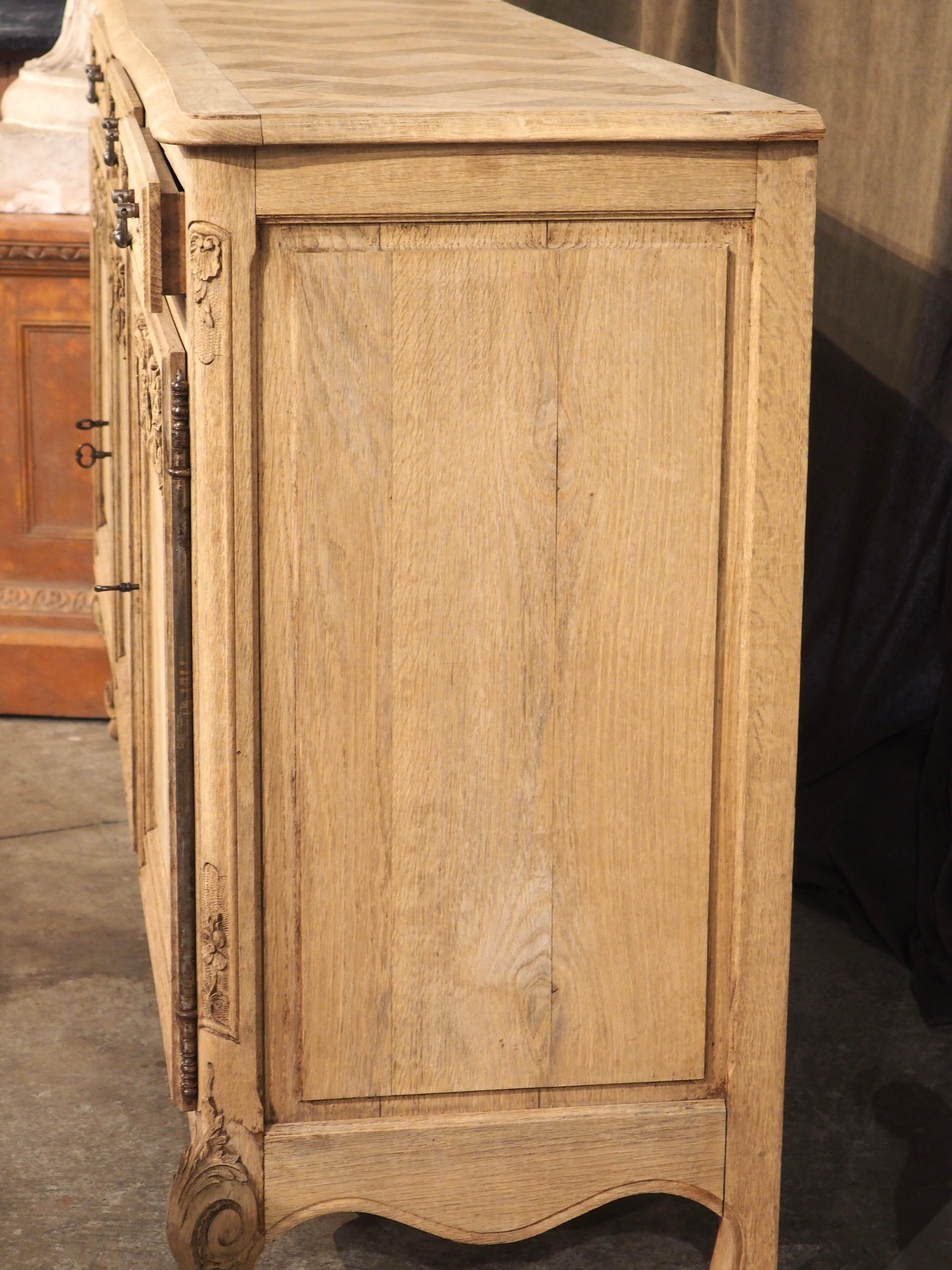 With an abundance of available storage compartments, this three-door French enfilade would make a fantastic addition to a dining room, living room, or bar area. Hand-carved in oak in the early 1900s, several Louis XV-style carvings embellish the
