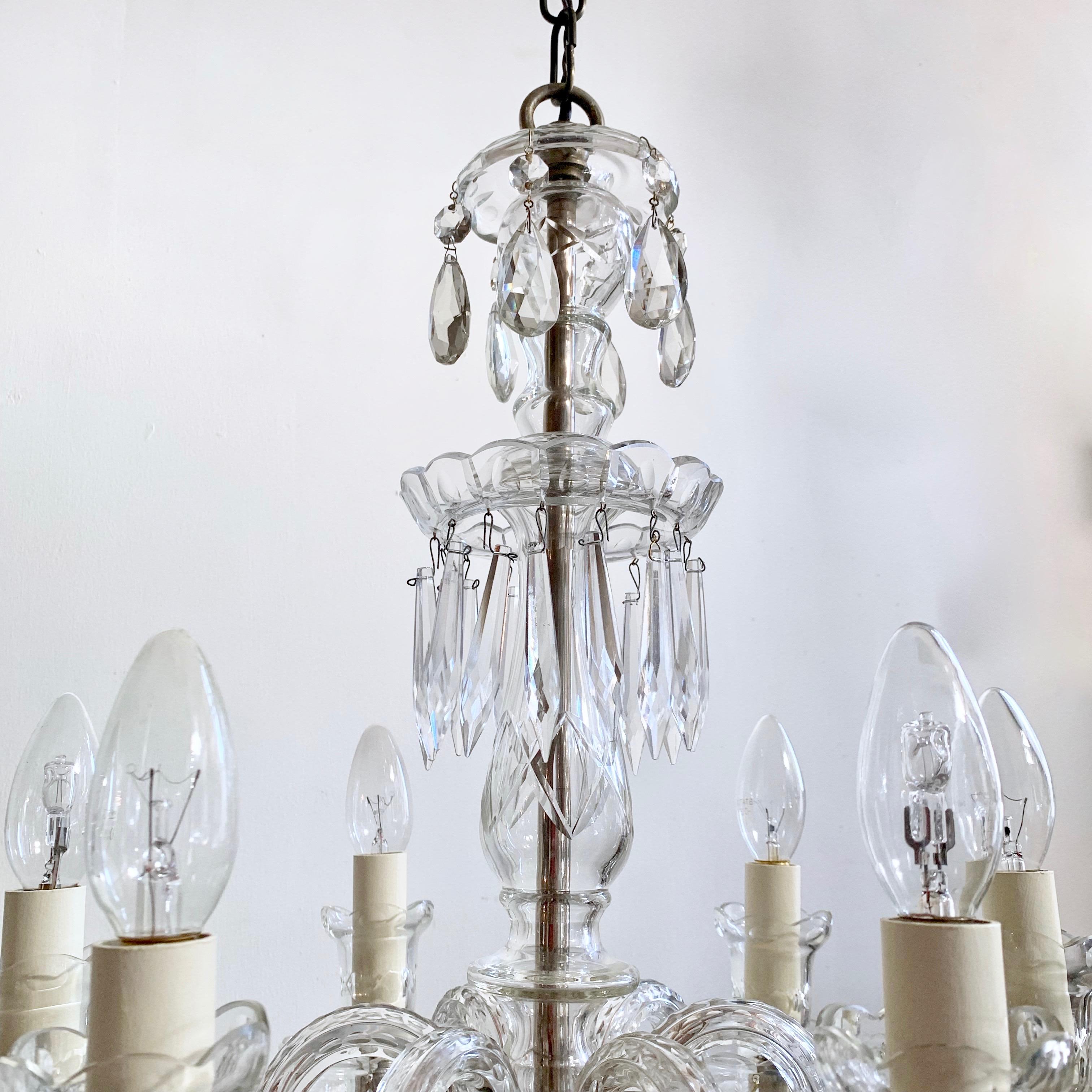 This Bohemian crystal chandelier originates from the 1930s Czechoslovakia. It’s six elegant crystal swan neck arms each hold a lamp. Retaining its original crystal drops it is dressed in unique cut crystal pear drops with crystal buttons and crystal