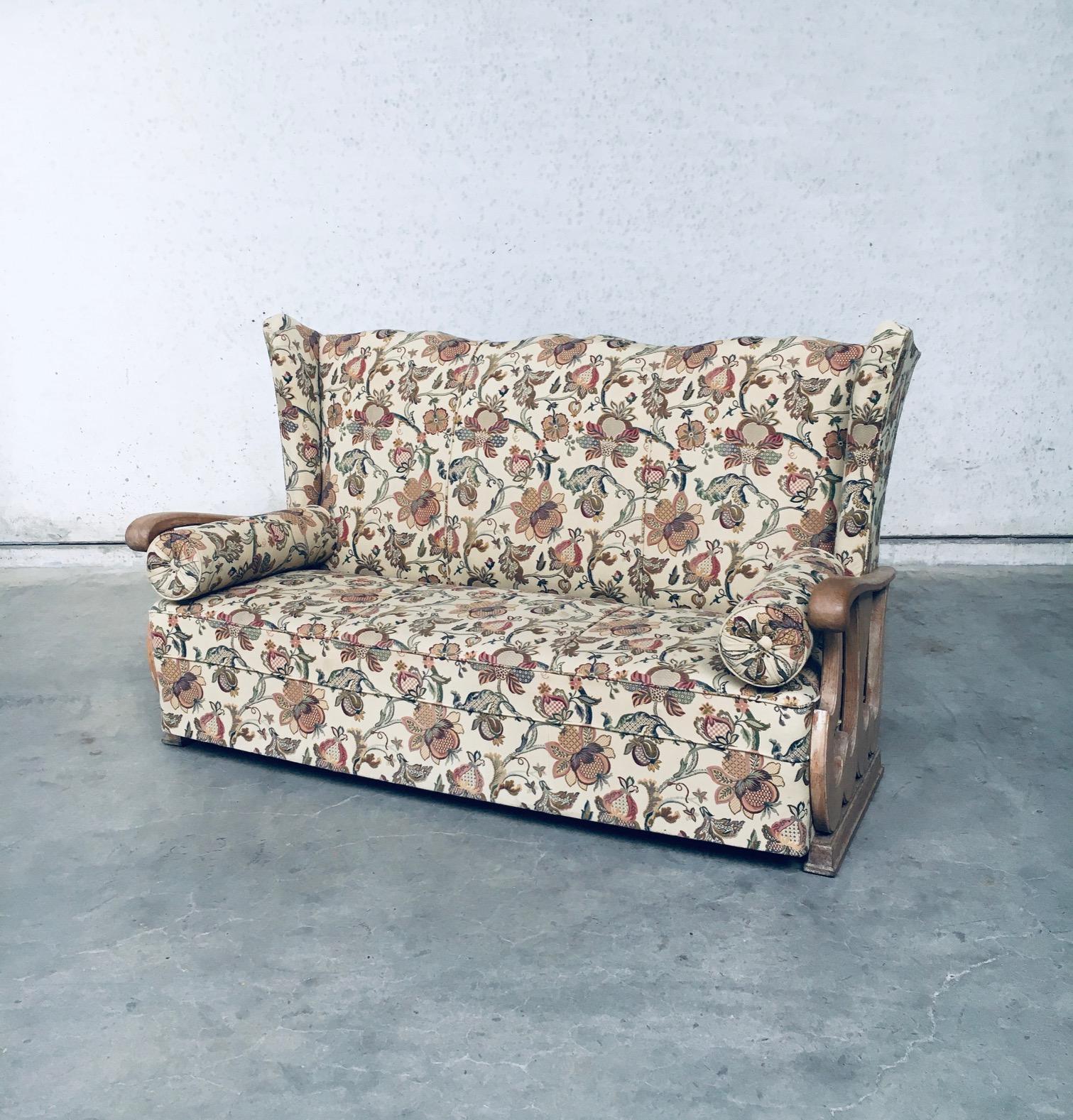 Original early 1900's design high wing back 3 seat sofa. Made in France, 1920's - 1930's. High wing back sofa with oak sculptural carved arm rests and recently reupholstered flower print fabric. This comes from the first owner who lived in a small