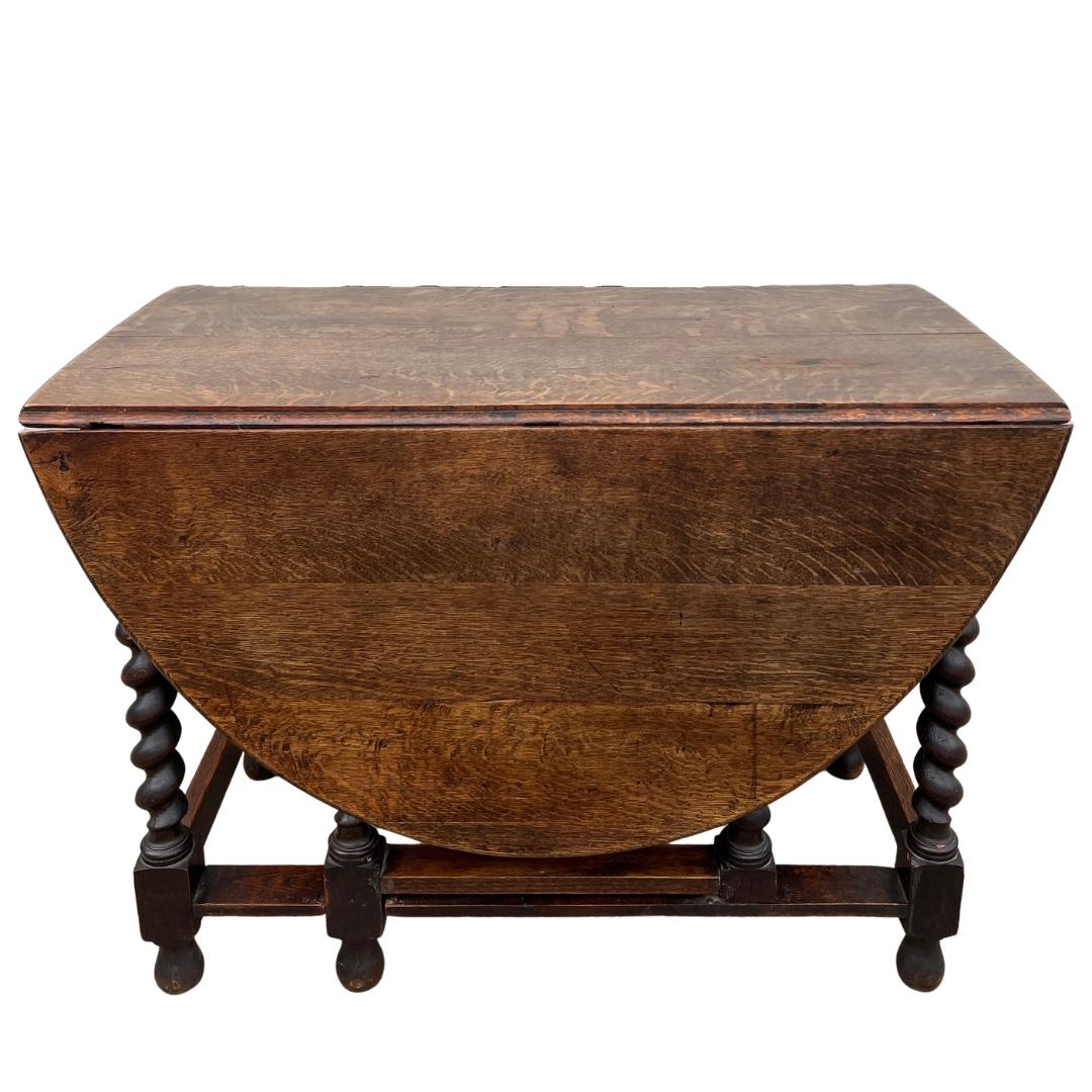 circa early 1900s England.

A gorgeous oak folding gateleg table, filled with old-world charm. The beautiful turned table legs, wood grain and warm patina are the highlights of this table. The sides of the oval table fold down, allowing it to be