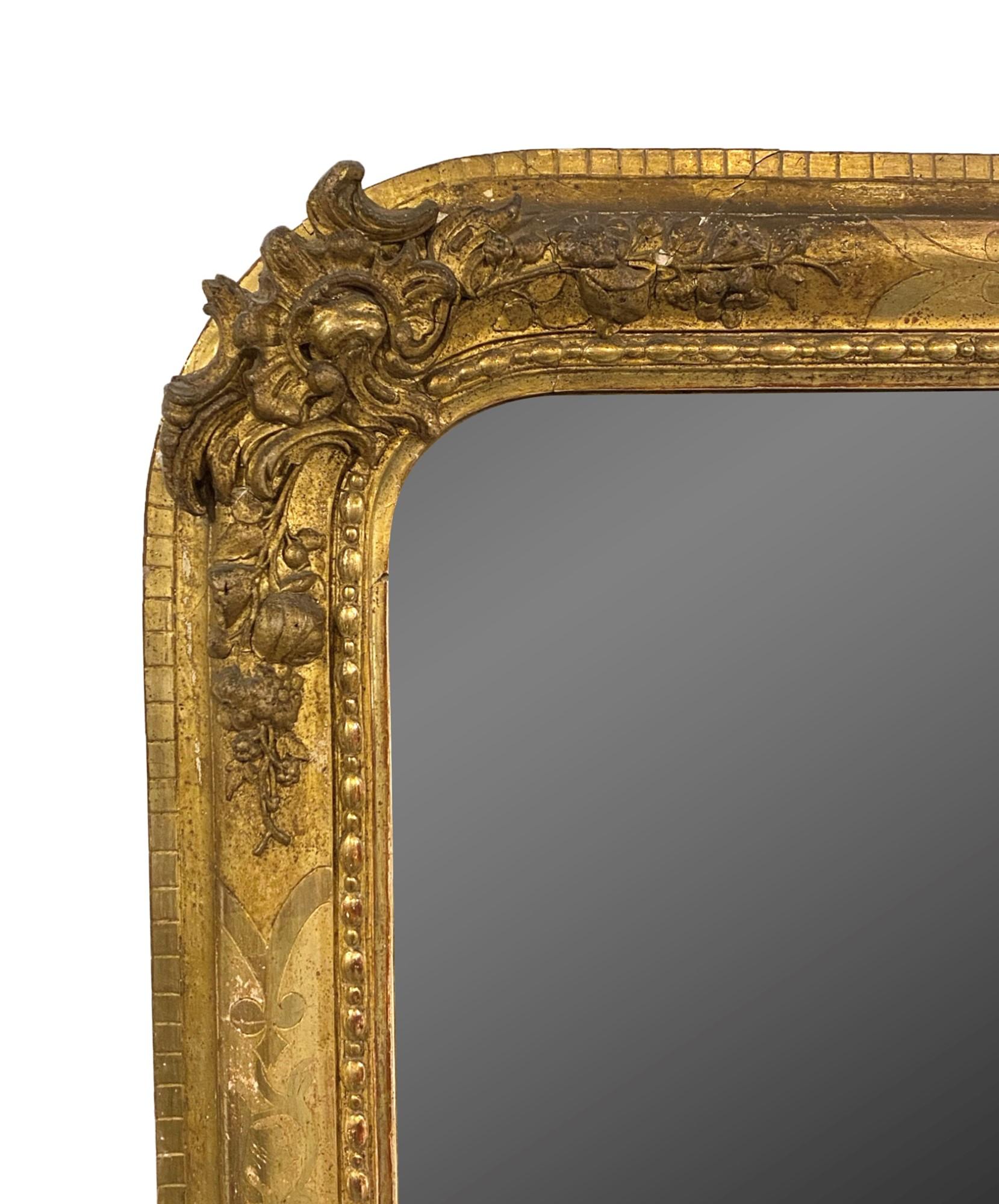 Hand carved wood and gesso framed mirror with floral designs and the original patina from the early 1900s. Original gilt finish with only minor losses to the frame. This was imported from Europe. This can be seen at our 333 West 52nd St location in