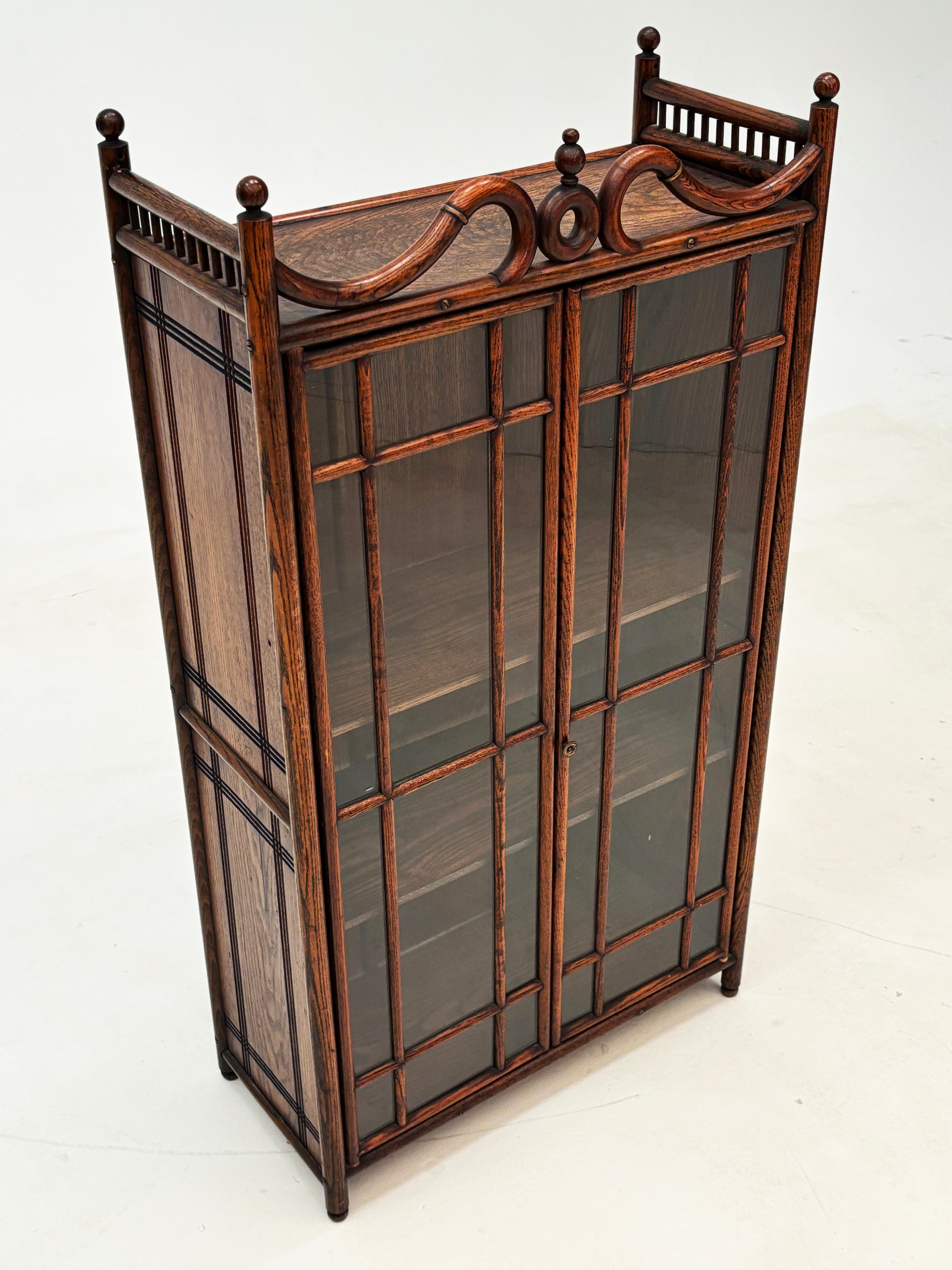 Questa piccola vetrina unica e sorprendente è un perfetto esempio di artigianato del legno del 1900. Con un tocco di Arts and Crafts, grazie alla splendida falegnameria in quercia mescolata con un po' di semplicistico estro del design dell'epoca