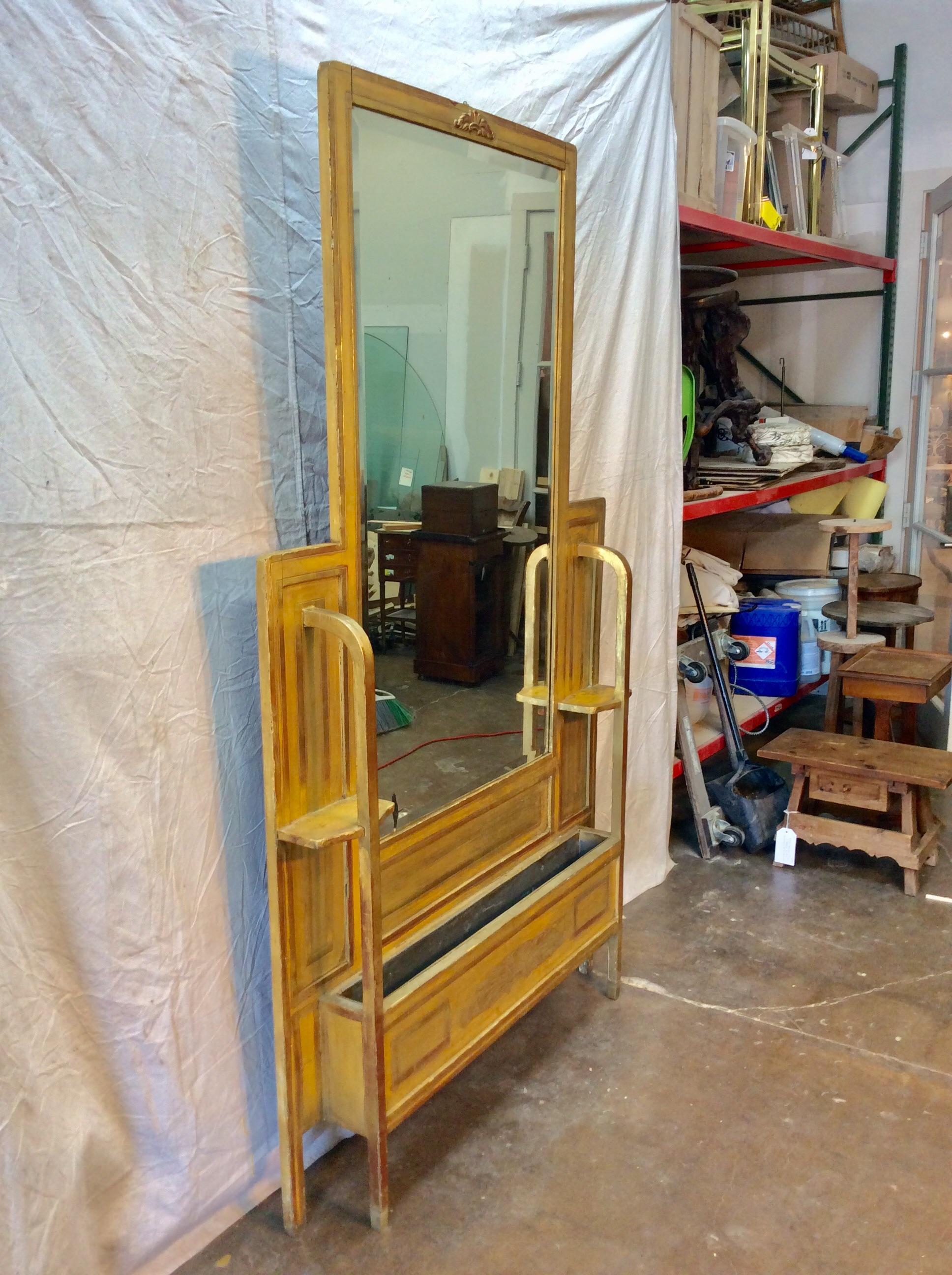 Trouvé dans le sud de la France, ce miroir de salle Art déco français doré du début des années 1900 a été utilisé dans un hôtel parisien. La pièce comporte un miroir biseauté orné d'une décoration feuillue dans sa partie supérieure. La base,