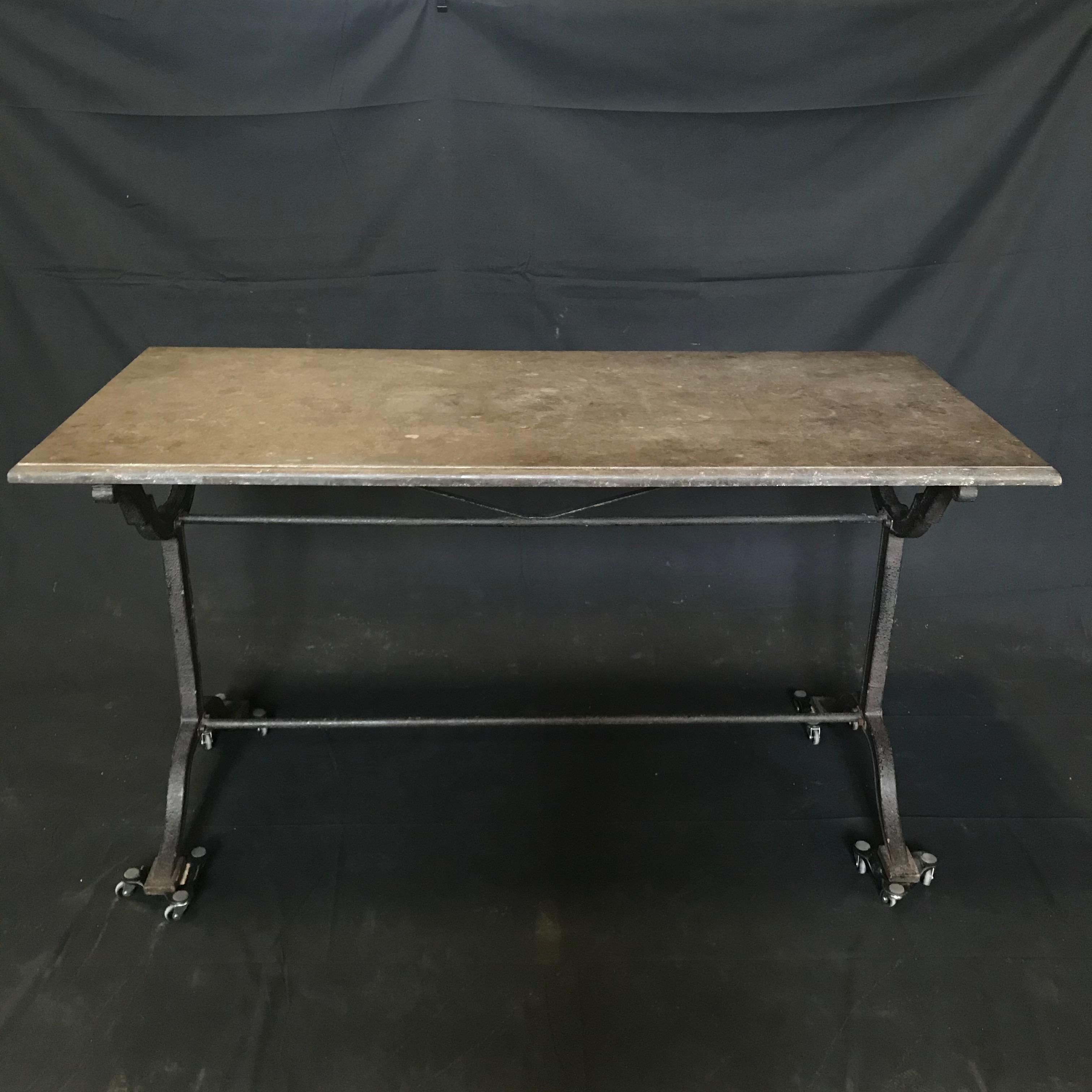 A classic French iron bistro table with grey stone top by L. Buchon, circa 1900. Weathered original gray stone top rests over a shapely wrought iron base from the St. Etienne, France. Elegantly curved stretchers add grace and allow for nice leg