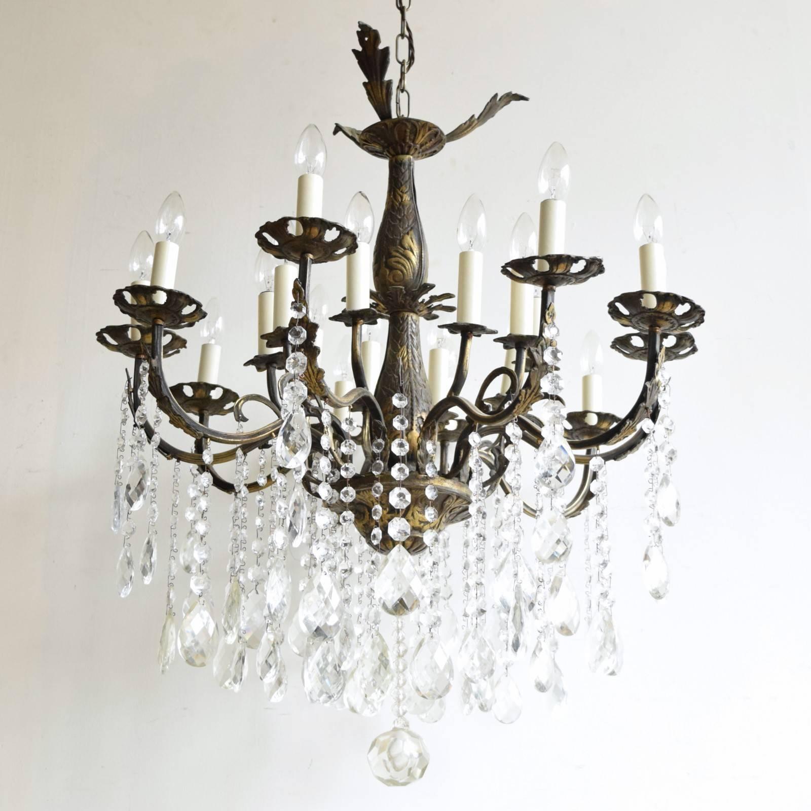 This large brass chandelier has sixteen lamps and dates from early 1900s, France. Its heavy cast brass frame has oxidised over time. We have taken care to leave this natural aged patina when restoring the piece. Dressed in strings of glass buttons