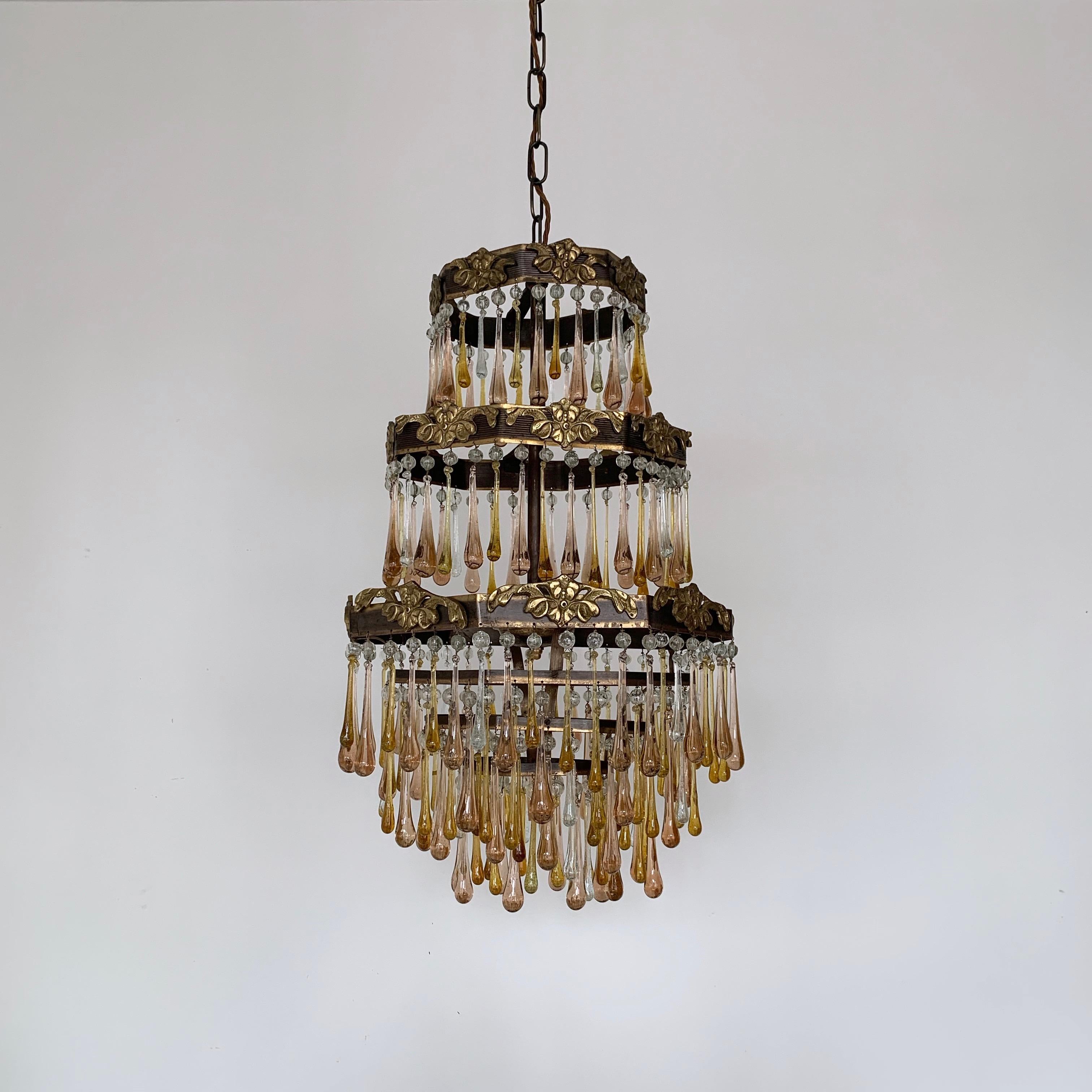 The frame of this peach and amber waterfall chandelier originates from 1920s France. It has been dressed in a mix of contemporary amber and clear glass teardrops with vintage enlarged peach drops, all finished with a clear glass bead. This