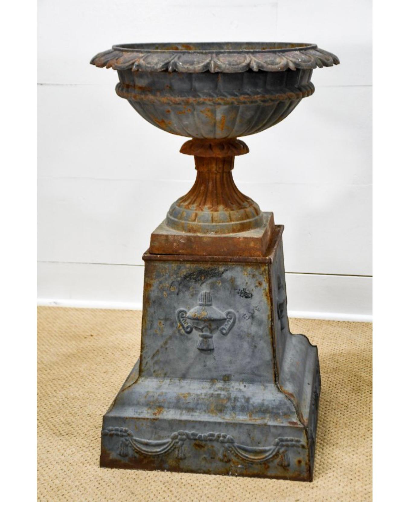 A strikingly and severely patinated matching pair of faded black cast iron garden urns raised on stepped plinth bases and decorated with reliefs of urn and ribbon. In the manner of Fiske. France, early 1900. 

Dimensions 21 Diameter x 35.5 Height