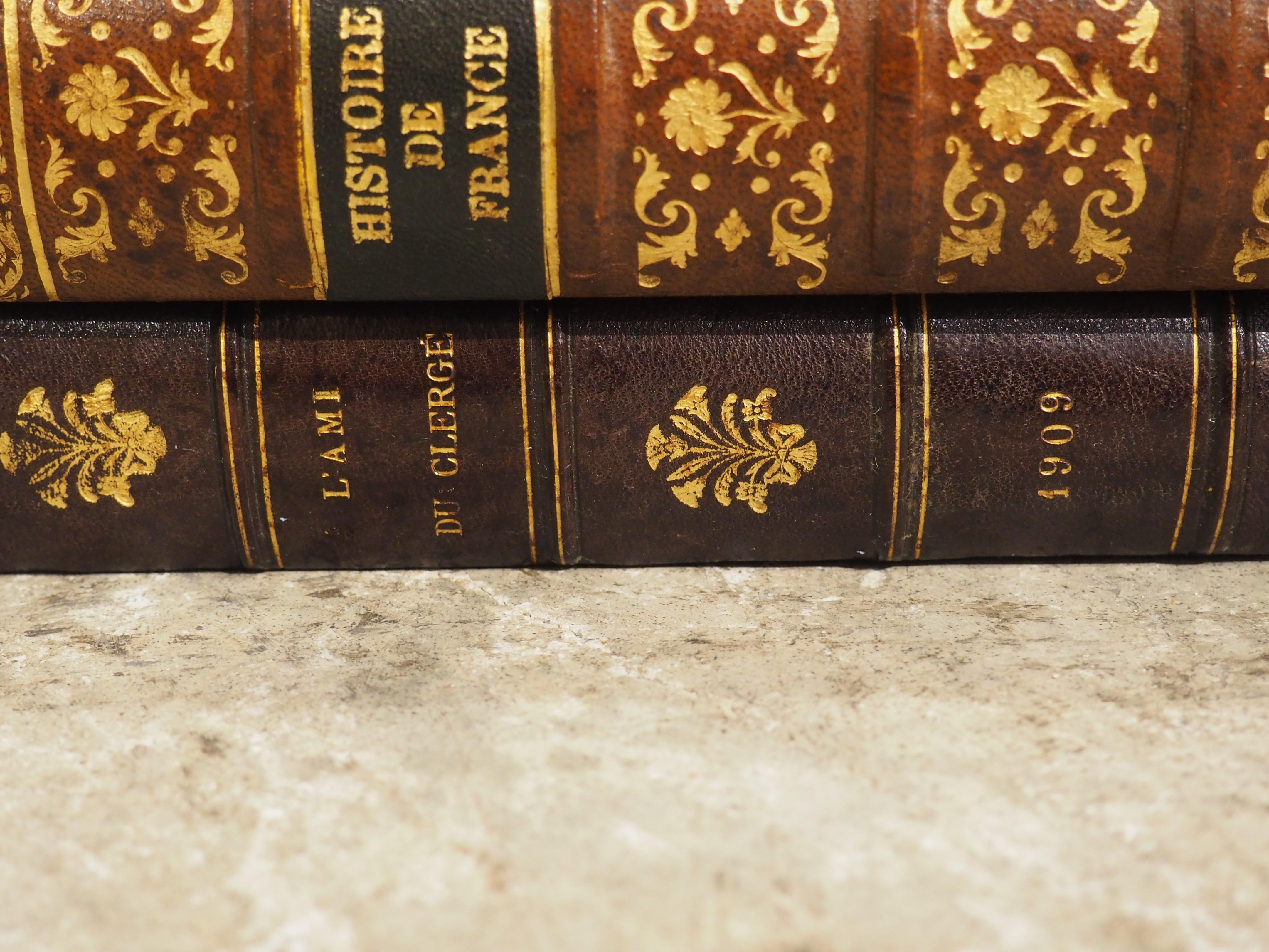This French cave à liqueur from the early 1900s appears as a leather-bound book stack. When in its closed position, the set depicts four historical books. Upon opening the lid, which is comprised of the top two books, the interior is filled with a