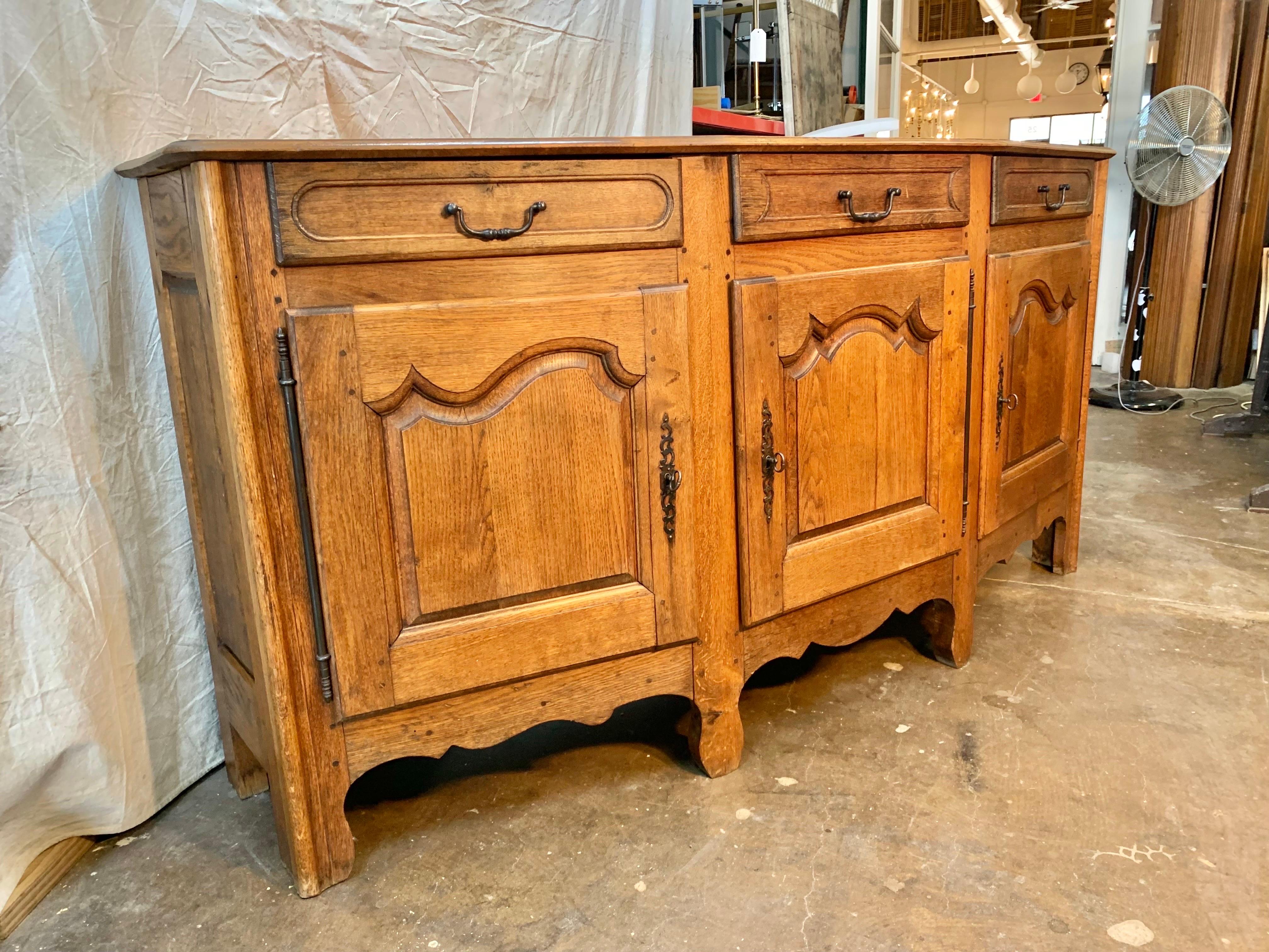 Found in the Burgundy region of France, this Early 1900s French Provincial Buffet or Sideboard was crafted by French artisans from old growth oak. Crafted with a unique angled front, the piece features a hand wood pegged top resting above three