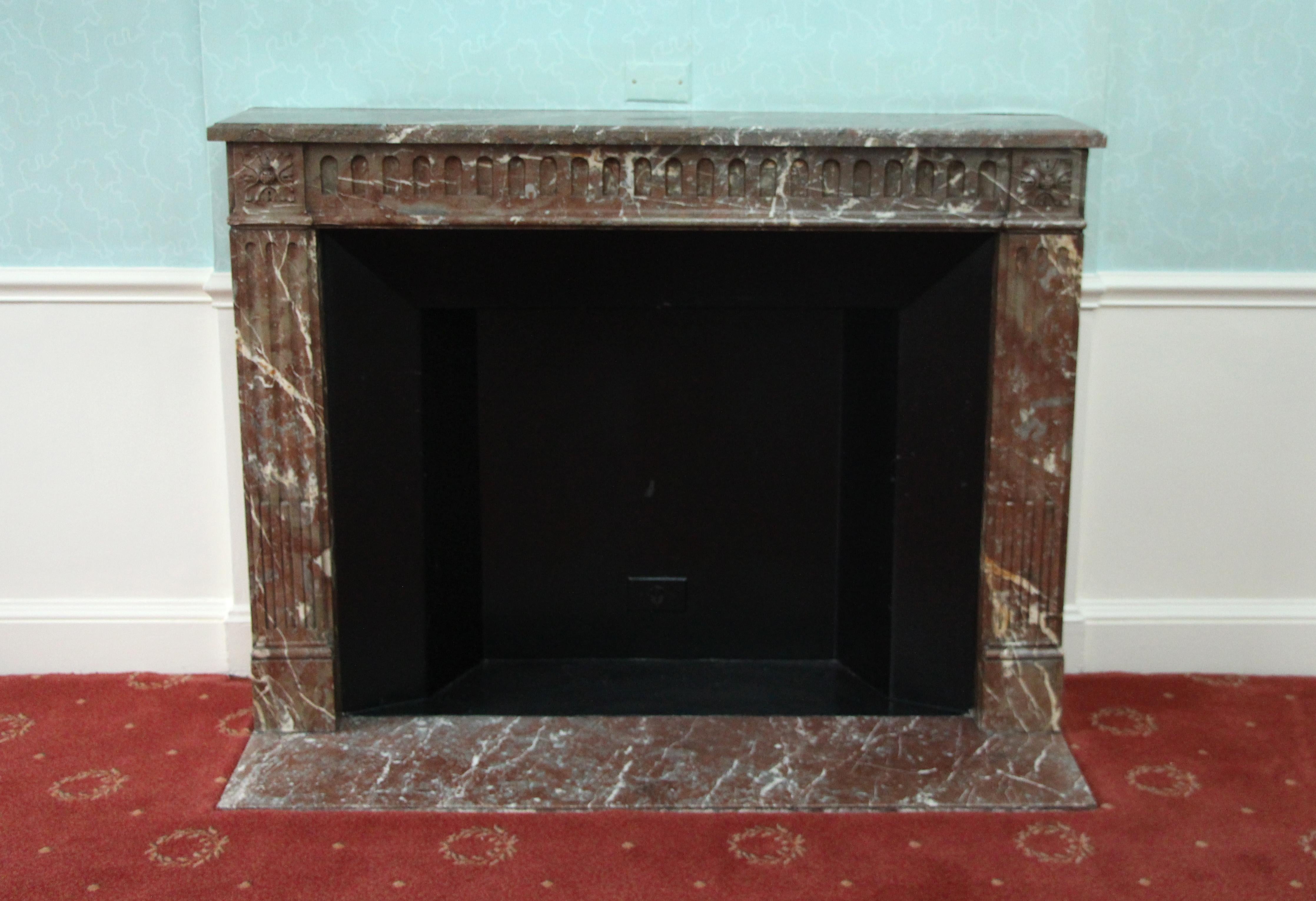 Hearth not included. Louis XVI French Regency earth tone brown marble mantel reclaimed from the most recent renovation to the Waldorf Astoria Hotel in New York City. This mantel was one of a group of antique mantels imported from Europe and
