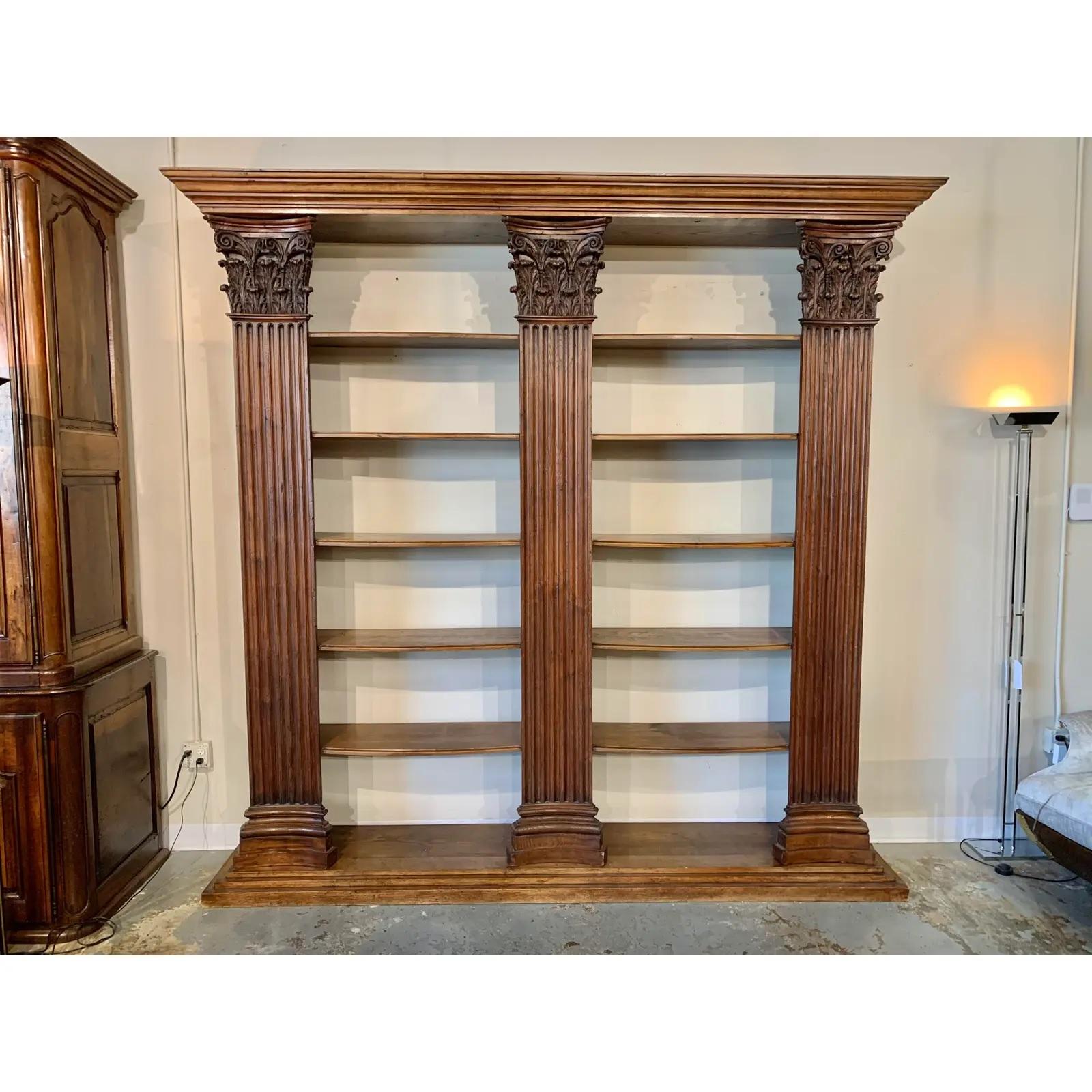 This handsome bookcase defines tradition and elegance with its superior build, handcrafted in France in the early 20th century using 18th century Corinthian hand carved walnut column facades. The columns are pegged on both the top and bottom to