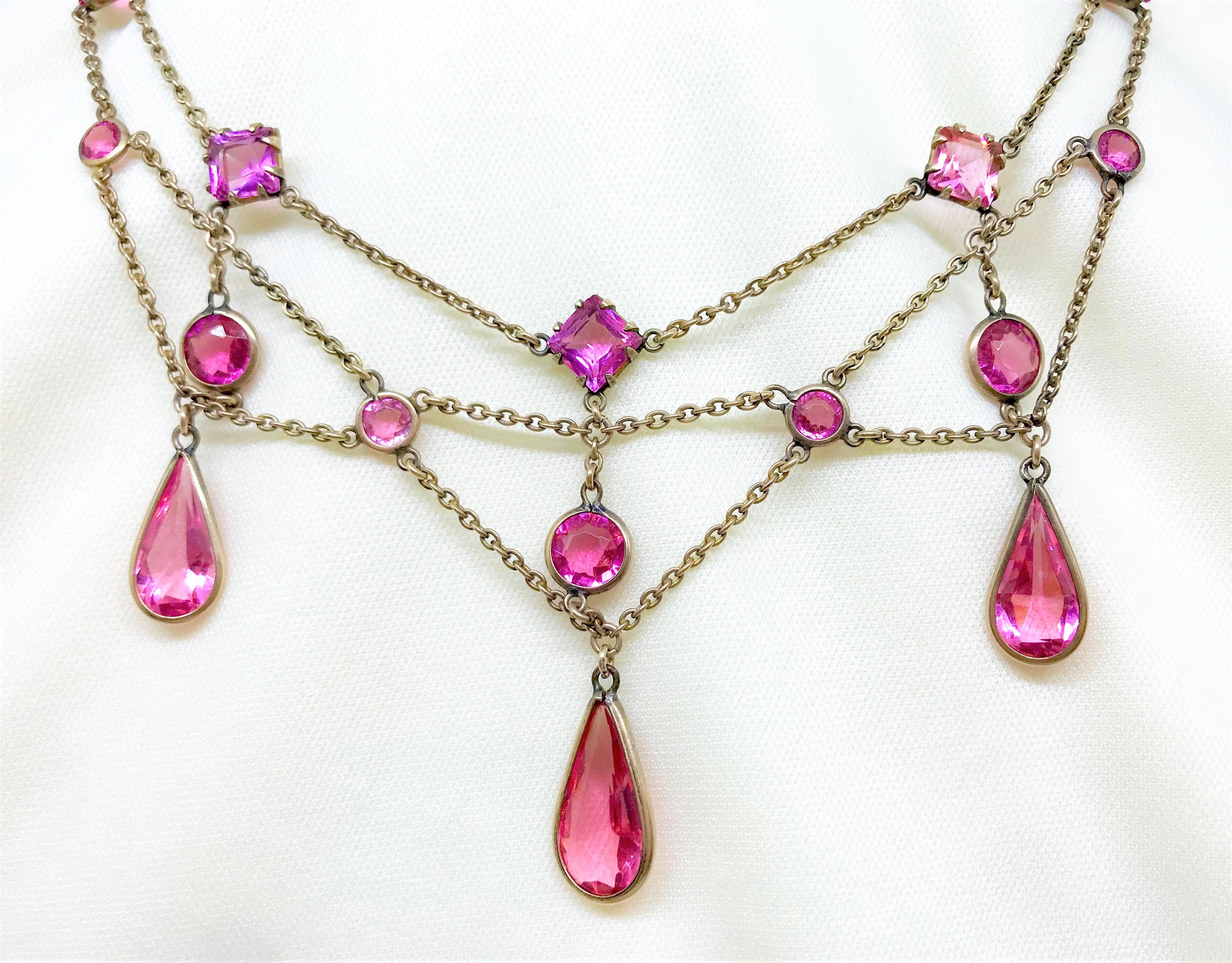 Early 1900s Gold-Filled chain festoon necklace bezel and prong set with round and square bright pink faceted glass stones.  The necklace is embellished with three larger bezel set pear-shape faceted drops at the bottom.  It measures 15.65