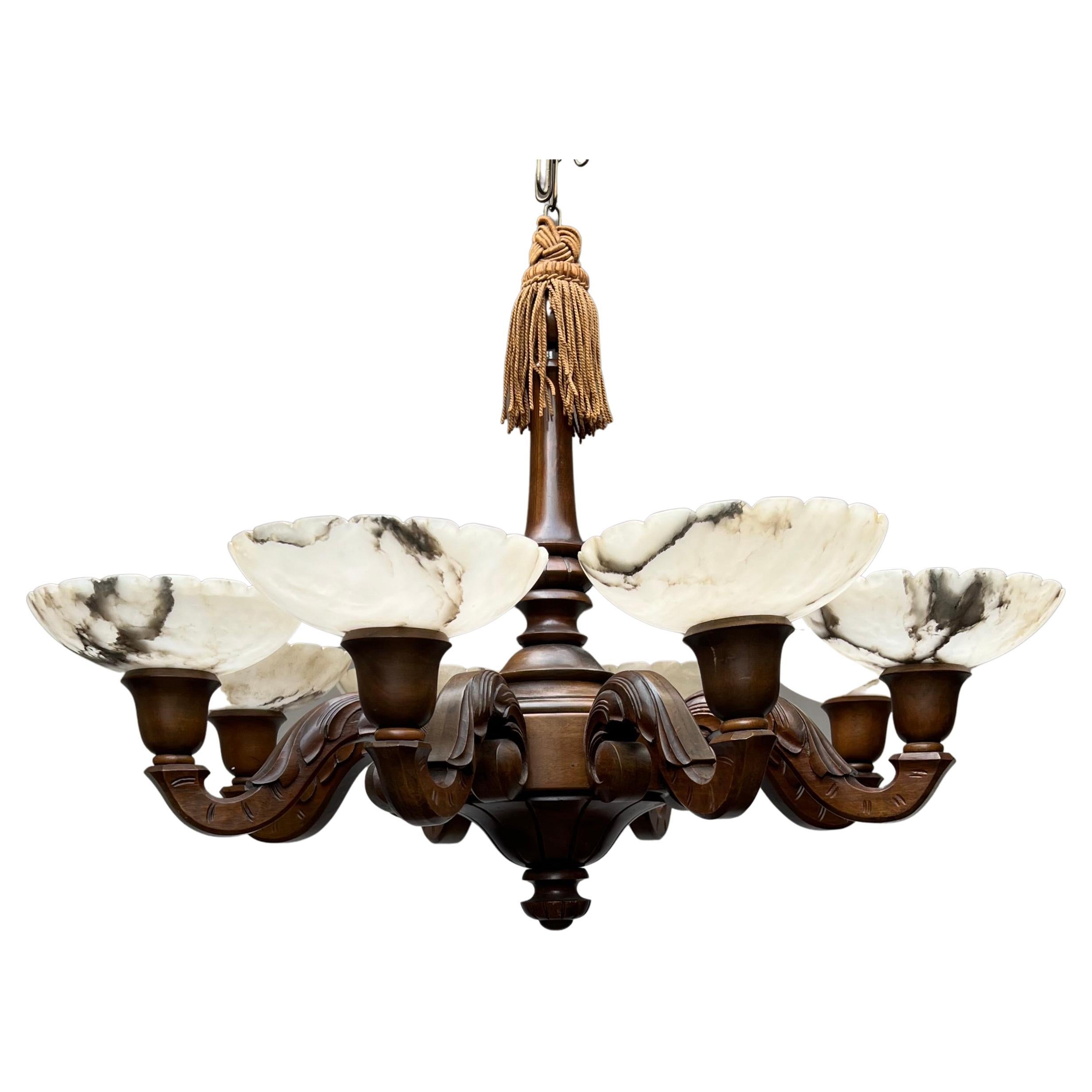 Beautiful handmade wooden pendant with eight alabaster shades.

This handcrafted neoclassical Revival chandelier from the early 1900s is of a wonderful, timeless design and it has a warm, nutwood patina. With as much as eight arms with alabaster