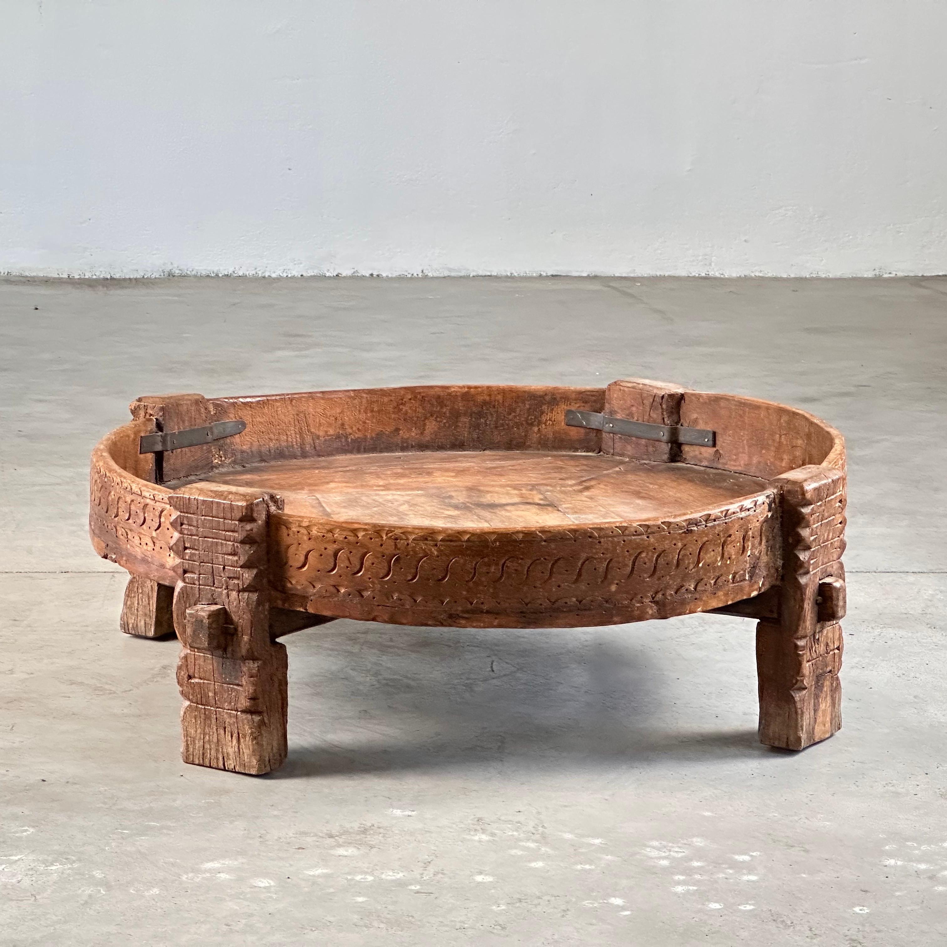 Cette table basse indienne circulaire unique, conçue à l'origine comme un moulin à chakki traditionnel, est un témoignage étonnant de l'artisanat sculpté à la main et de l'héritage culturel. Fabriqué en bois massif avec des incrustations de fer