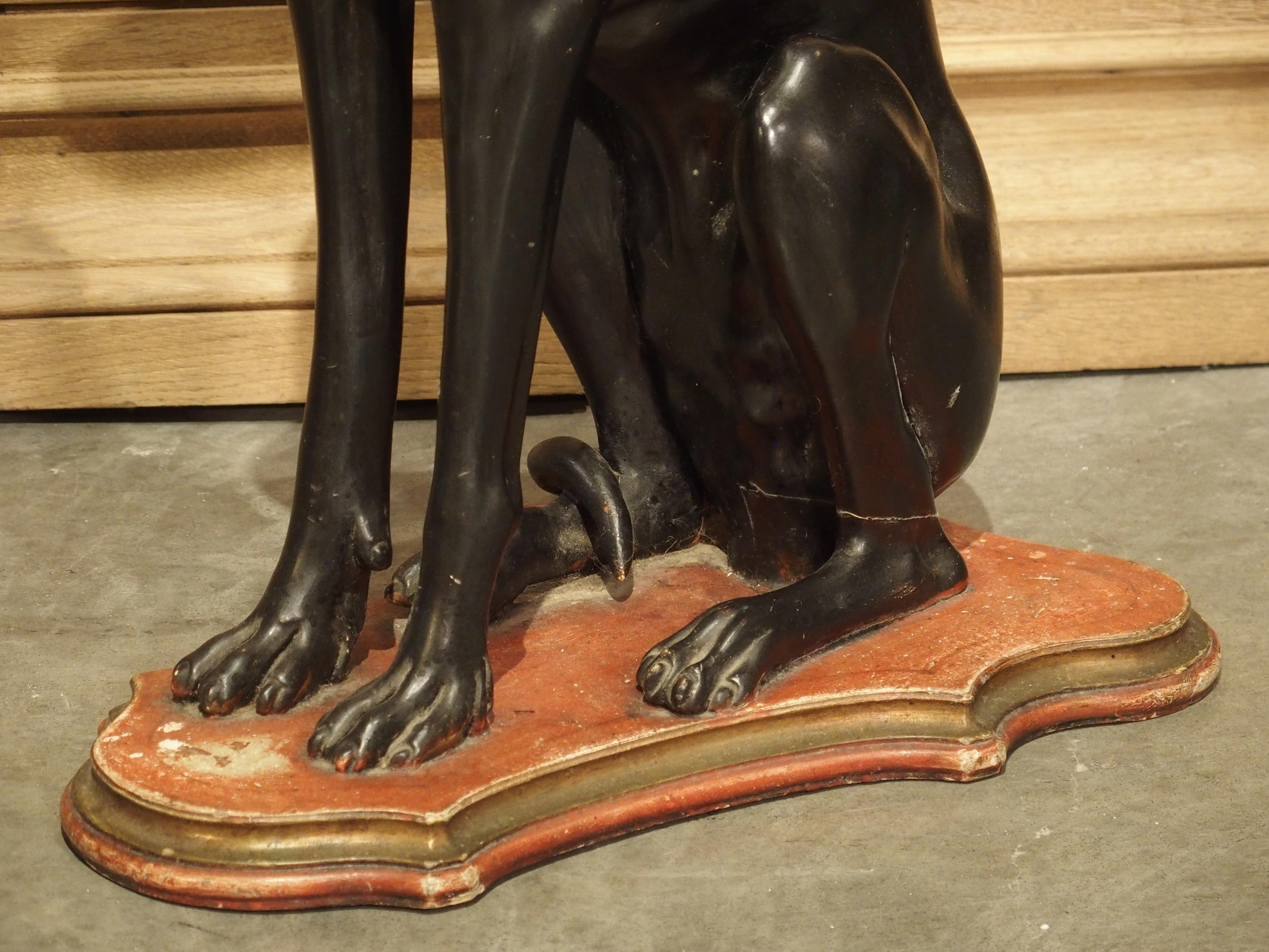 Carved and painted in Italy in the early 1900s, this statue of an Italian greyhound is a must have for any dog lover. The Italian greyhound is known for being a playful, affectionate, and alert dog. Here, we see the dog sitting attentively, as if