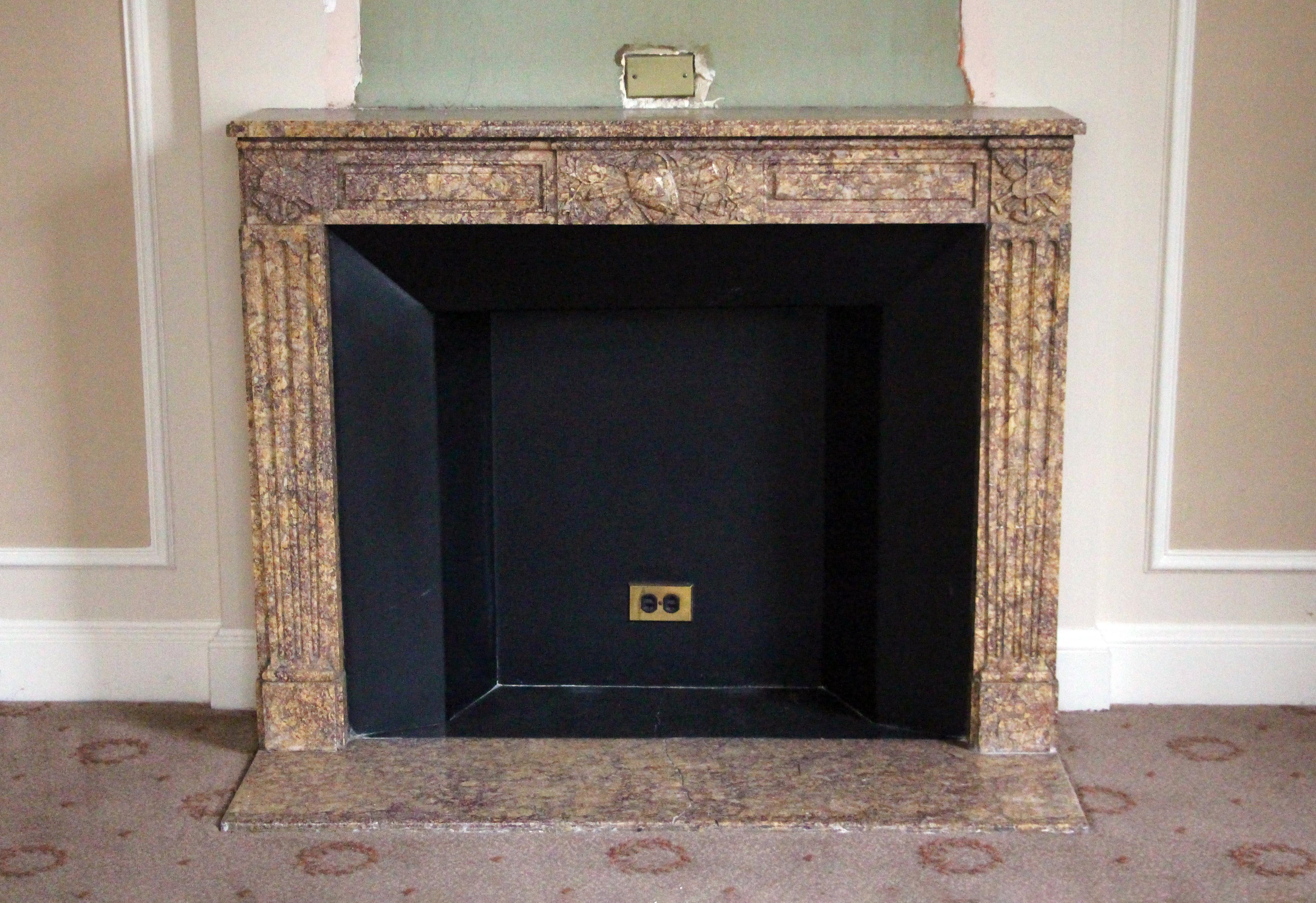 Hearth not included. This mantel, original to the M Suite on the 28th Floor of the Waldorf Astoria Towers is carved in a Louis XVI Regency style from earth tone brown marble. Floral and fluted column details enhance the beauty of this simple yet