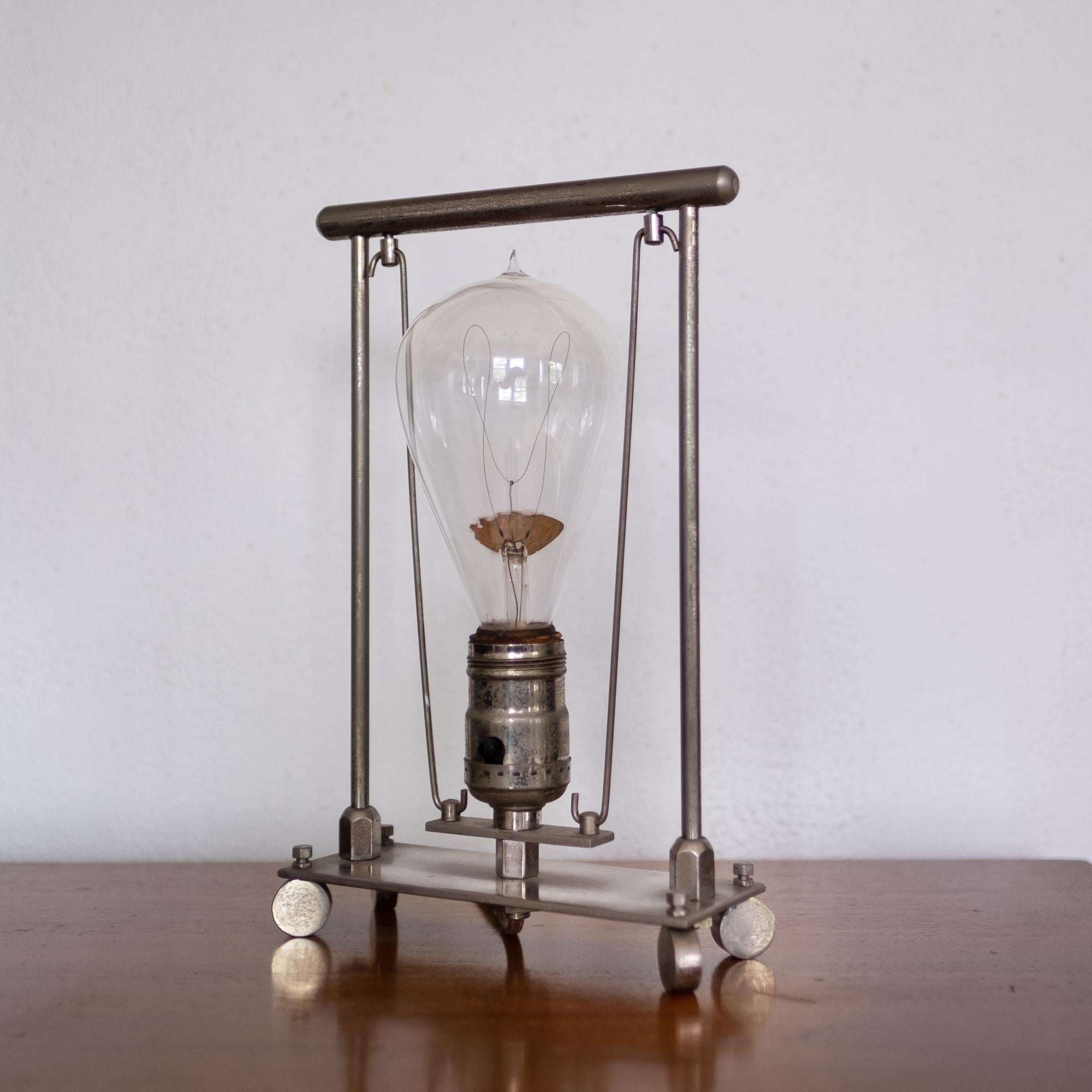 Early 1900s modernist lamp. Nickel-plated steel. Includes a NALCO carbon filament balloon bulb. Will take a modern bulb which would be recommended for daily use.