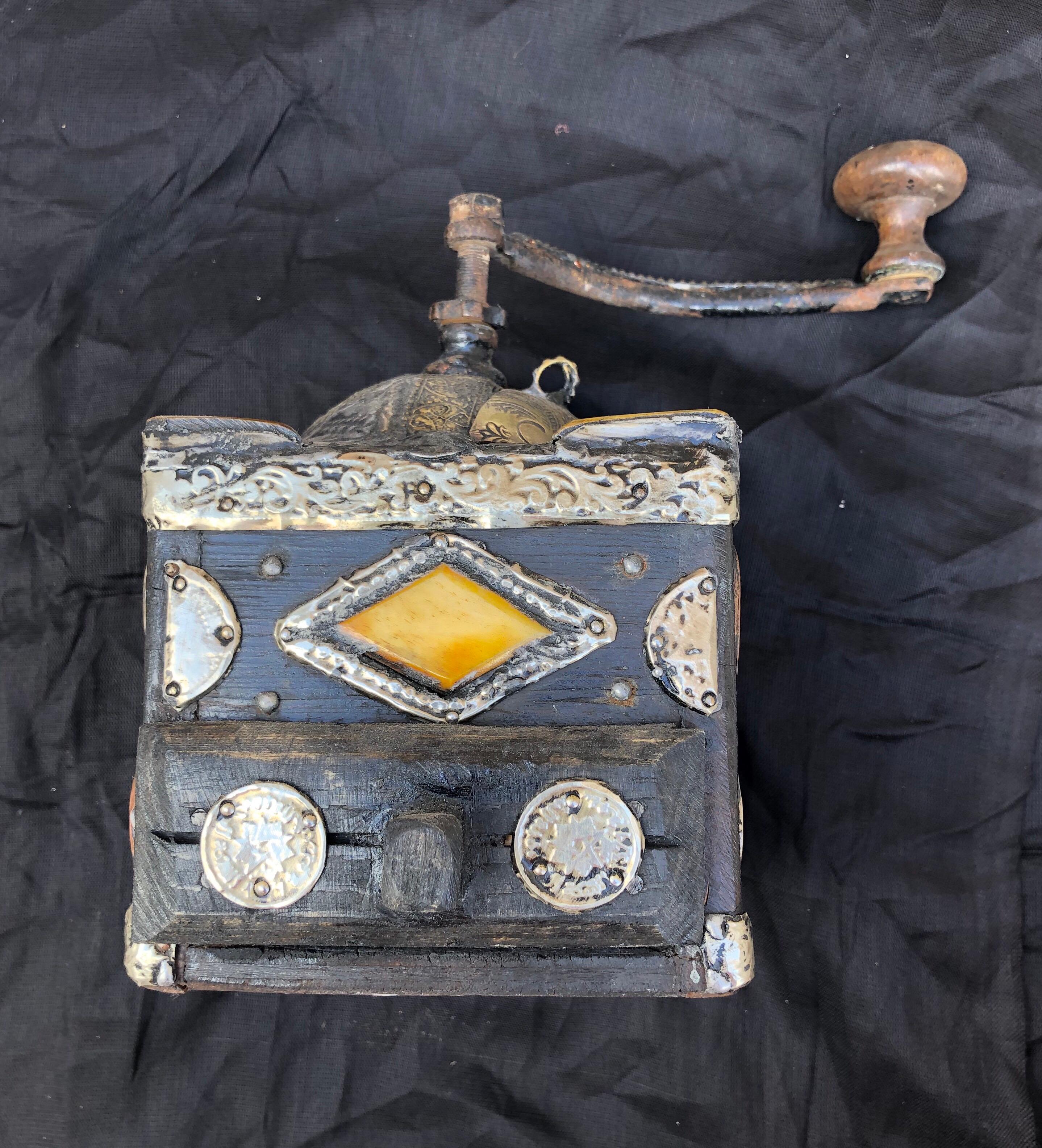 This antique hand-crank grinder is made of tamarisk wood, with hand-engraved silver melange adornment, hand carved embellishments, and numerous antique coins. Entirely handmade, this grinder was used by southern Morocco nomads while traveling and