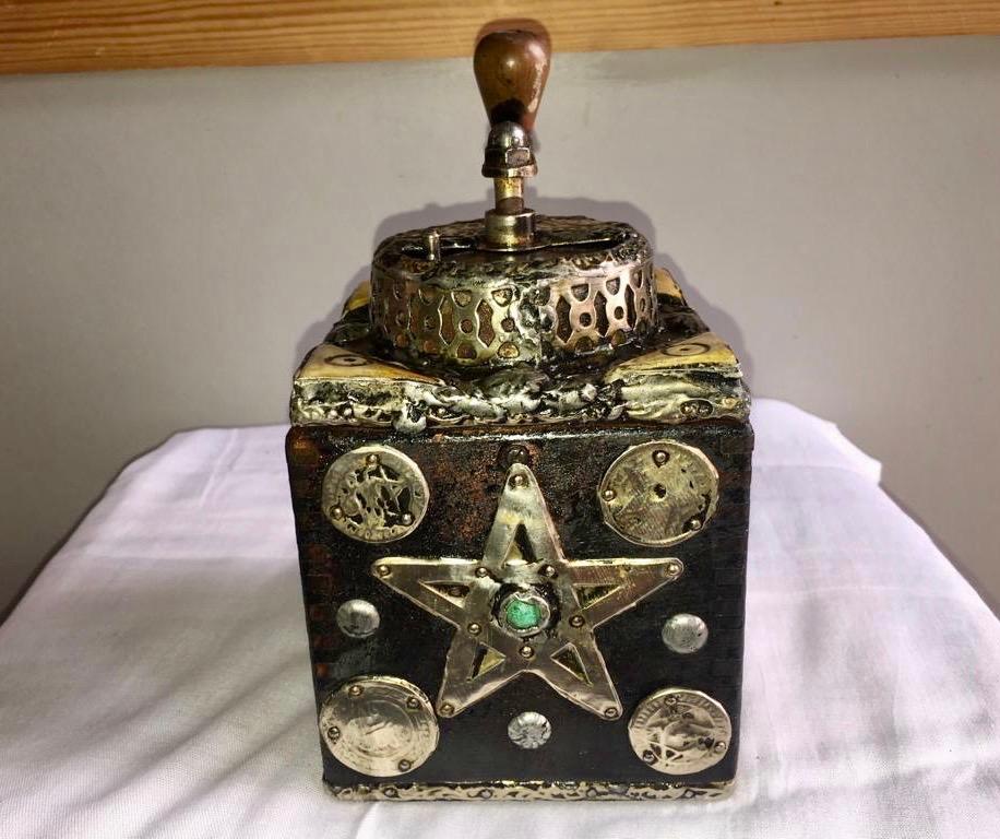 This antique hand-crank grinder is made of tamarisk wood, with hand-engraved silver melange adornment, hand carved camel bone embellishments, and numerous antique coins. Entirely handmade, this grinder was used by southern Morocco nomads while
