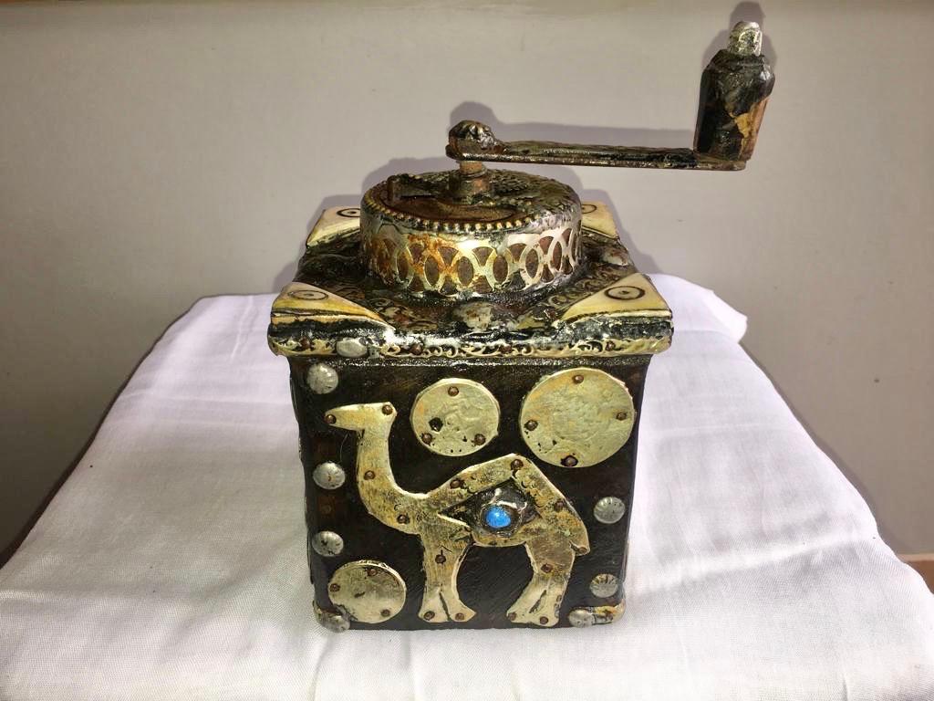 This antique hand-crank grinder is made of tamarisk wood, with hand-engraved silver melange adornment, hand carved camel bone embellishments, and numerous antique coins. Entirely handmade, this grinder was used by southern Morocco nomads while