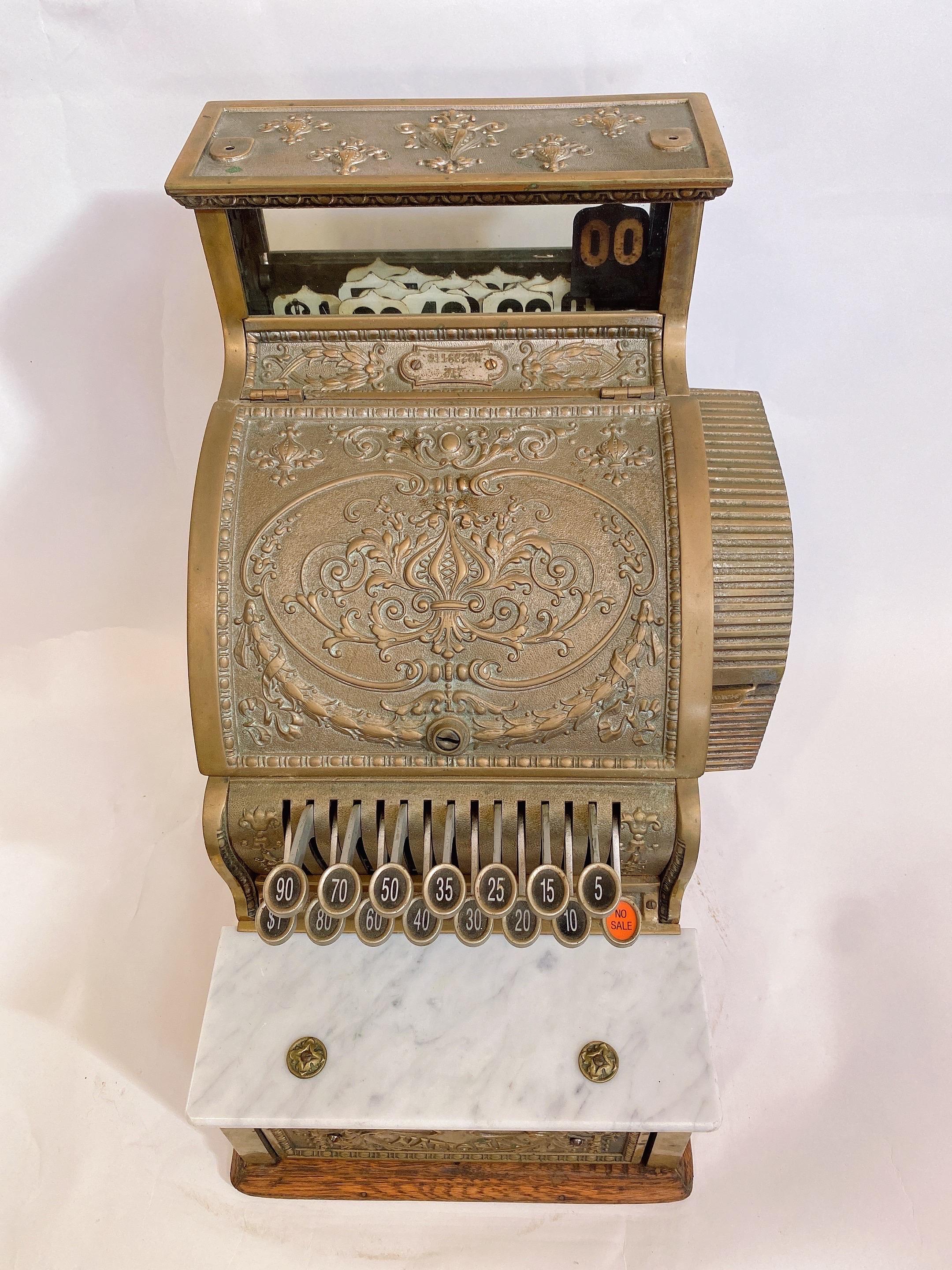 Early 1900s national brass cash register, used cash register by National Cash Register Co. It is still functioning well. This register is mounted on a solid wood desk, also in good condition. There is a small piece of white marble of the plate above