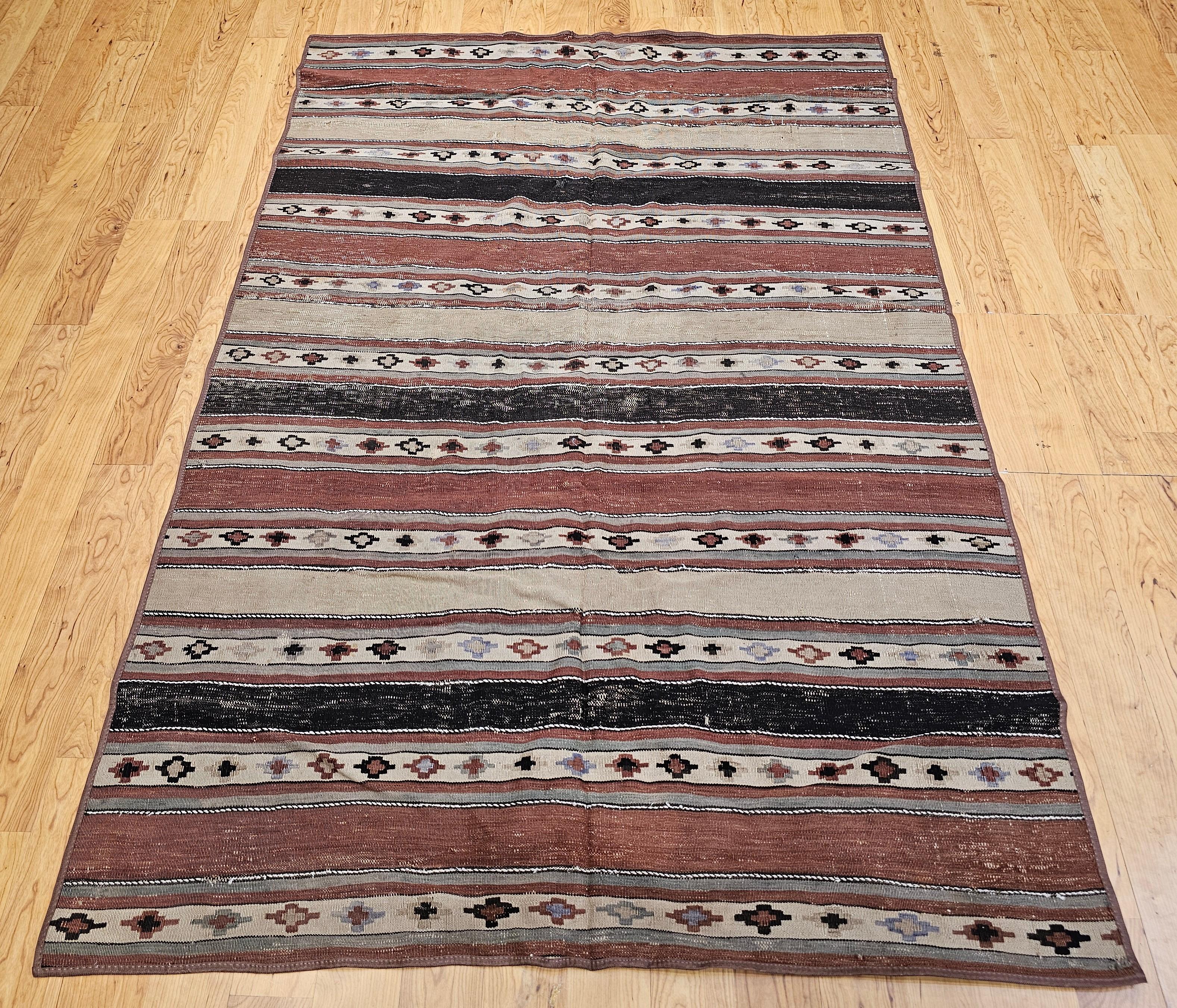 This early 1900s Persian Shahsavan Kilim is a rare and beautifully preserved textile, handwoven in a wide-band pattern that echoes the aesthetic of larger Native American Navajo rugs. Crafted over a century ago by the nomadic Shahsavan tribes of