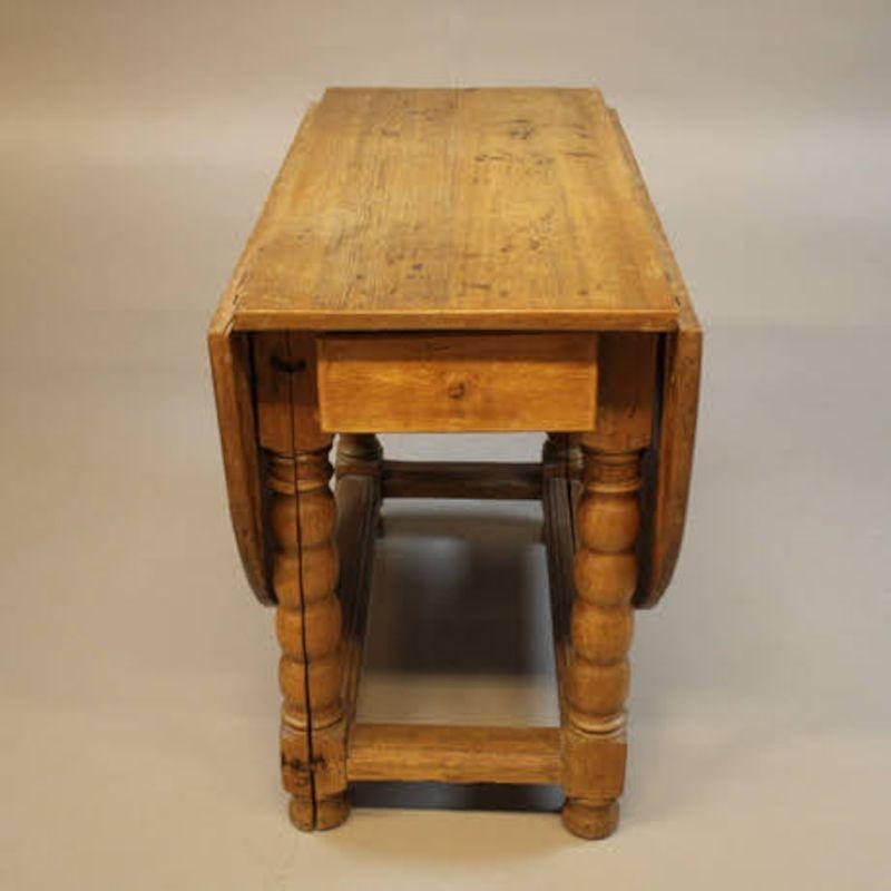 Early 1900s Swedish pine gateleg dining table. Turned legs, single drawer on either side. Folds out to oval dining table, small rectangle table for two when collapsed.

H 30.5