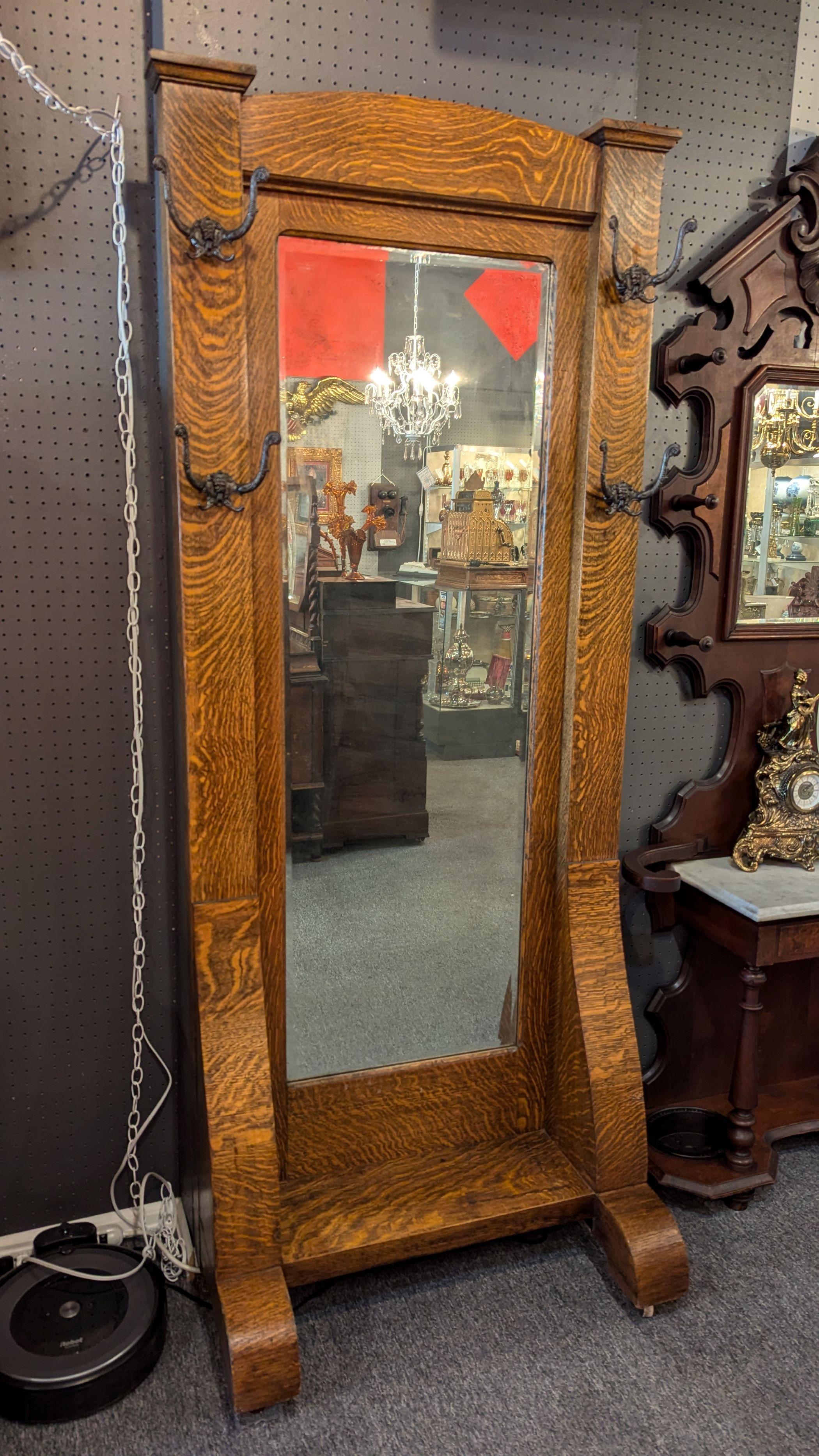 Turn on the century quarter sawn, tiger, oak hall mirror with coat and hat hooks.  Substantial antique piece, 82' tall, showing beautiful oak grain, original beveled mirror with patina, four double hooks, and step rest for shoe tying.