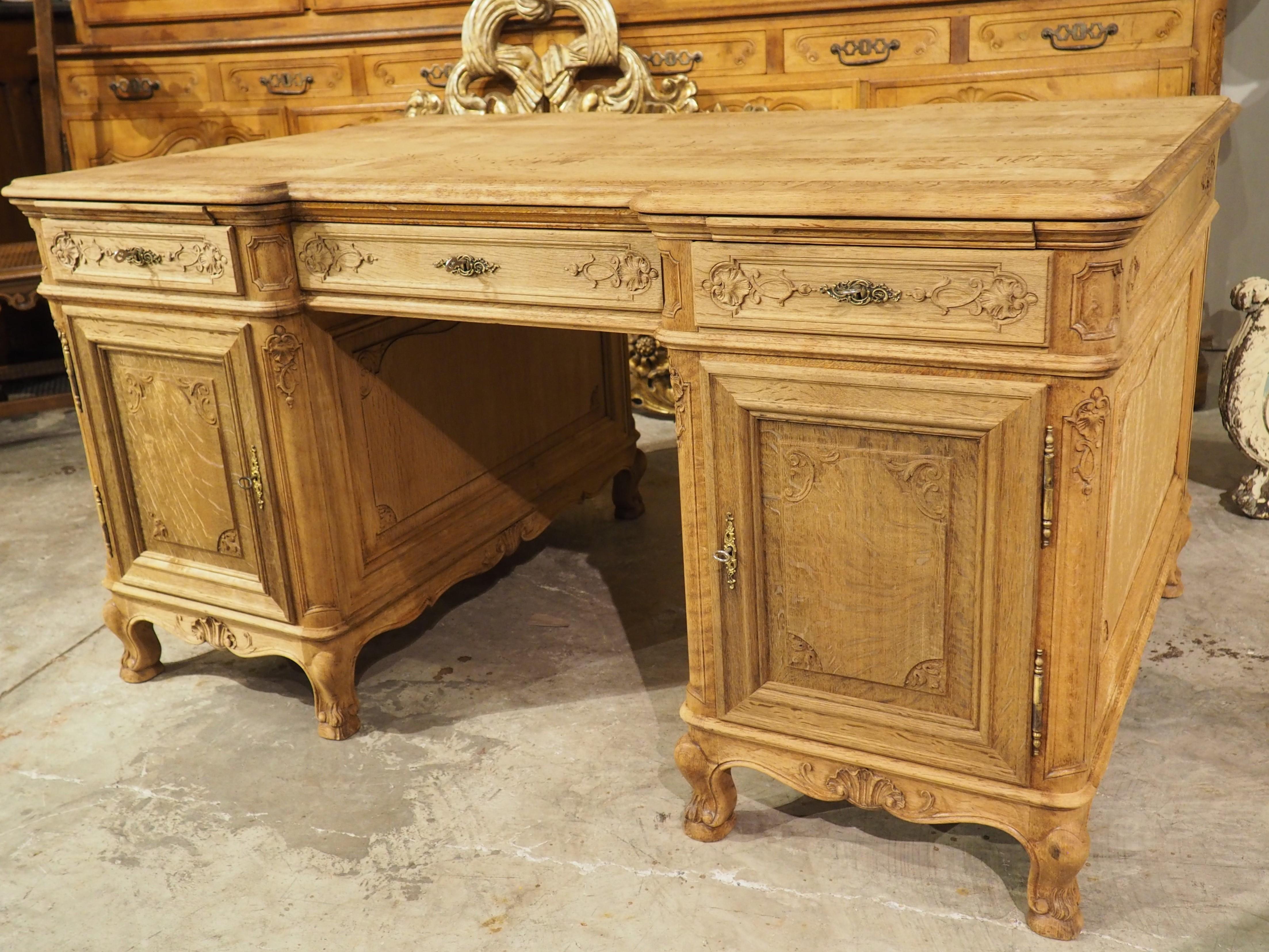 As a transitional age in French history, the Regence period is known for furniture that showcases forms of the preceding period (Louis XIV), as well as early Louis XV stylings. In the case of this bleached oak partner’s desk, the motifs are