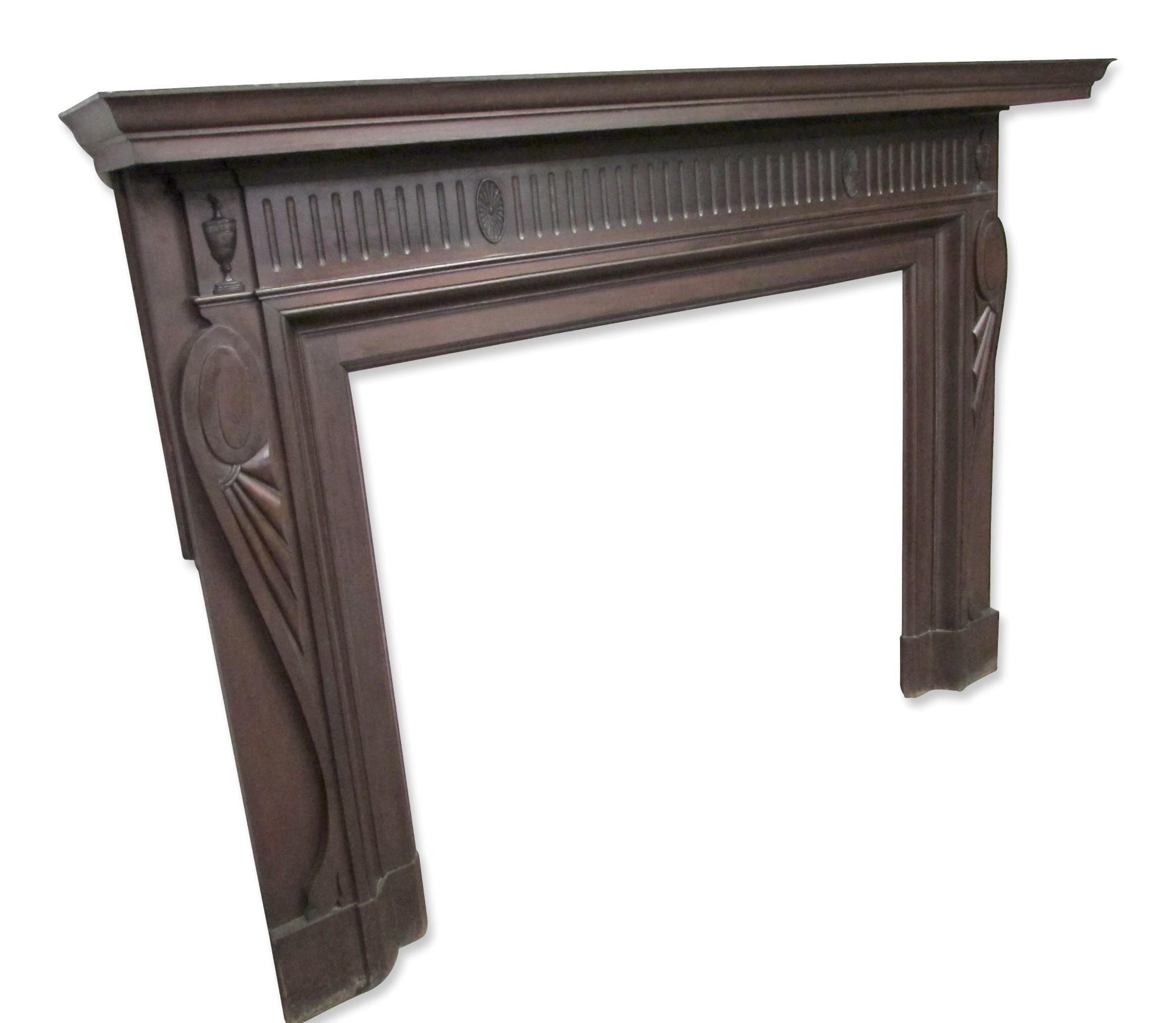 Original turn of the century carved mantel with original finish. The wood appears to be mahogany with carved urns and web details. Swirl and fold detail on sides adds a transitional detail. The mantel is wide with a protruding shelf consistent with