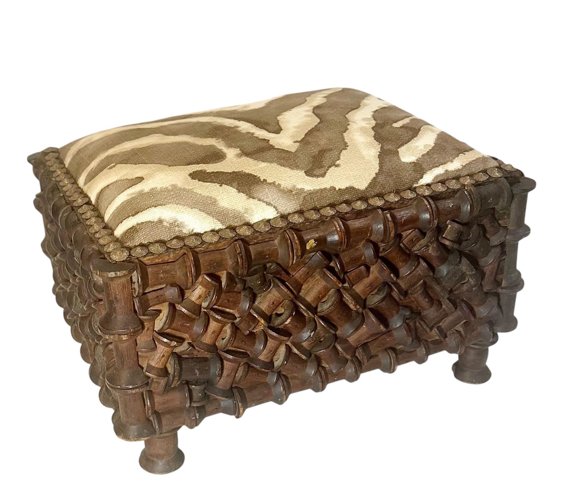 A rare and distinctive tramp art footstool, handcrafted from wooden thread spools in the early 1900s. This remarkable piece exemplifies the ingenuity of tramp art tradition, where discarded materials were repurposed into functional works of folk