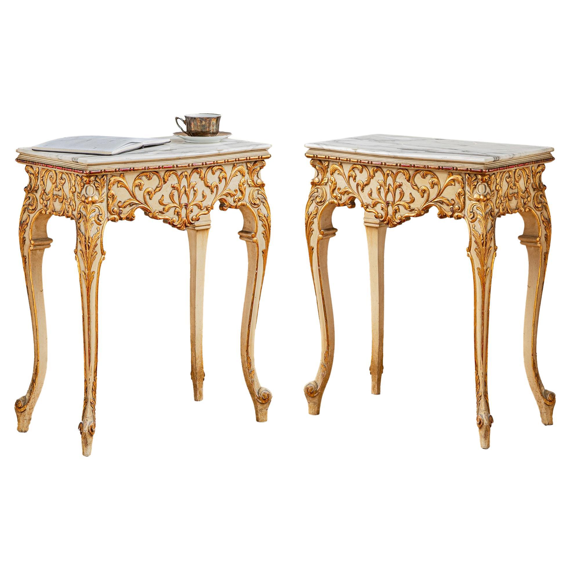 A pair of elegantly embellished venetian style bedside tables from Naples, Italy. The pair of tables, with concealed drawers, stand on long cabriole legs and adorned with intricate, Rococo style carvings on all visible sides. They are painted in the