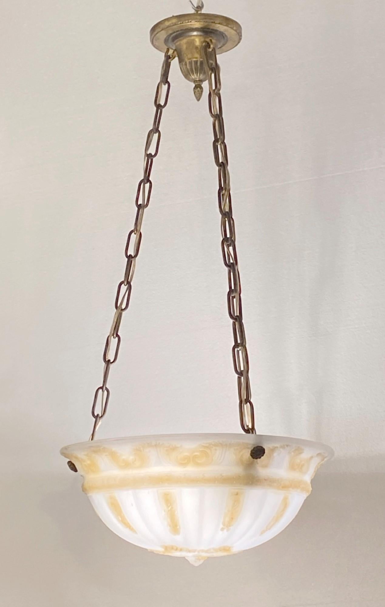 Early 1900s white cast glass dish light with raised details highlighted with an amber hue. Features brass hardware and uses two standard household light bulbs. Chain can be adjusted. This can be seen at our 2420 Broadway location on the upper west