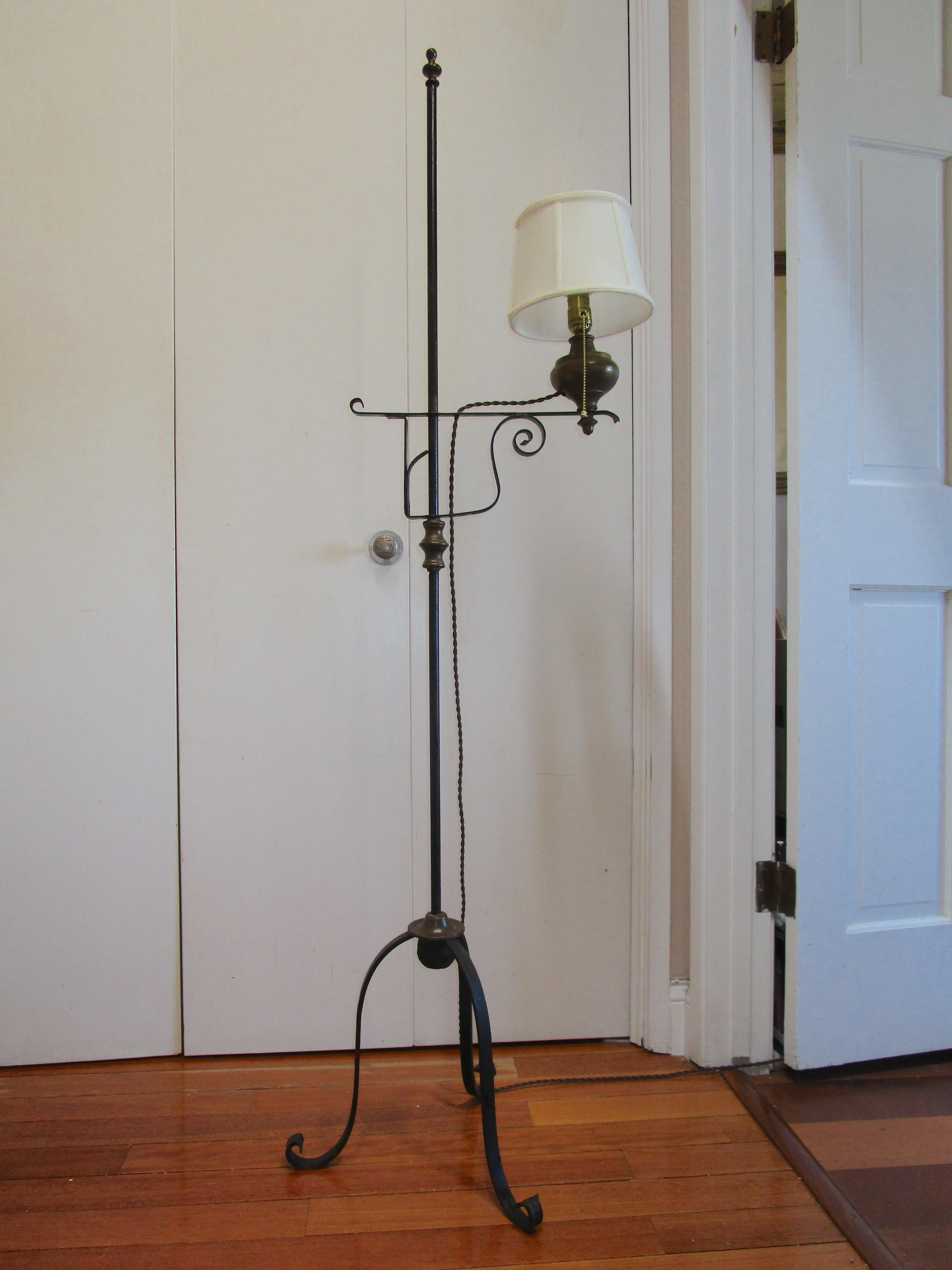 Dies ist eine auffällige schmiedeeiserne Lampe mit Dreibeinfuß. Das Ölreservoir, die Kordel im Vintage-Stil und das Dreibein, das auf verschnörkelten Füßen ruht, machen ihn zu einem echten Hingucker. Dies ist eine verstellbare Stehlampe aus