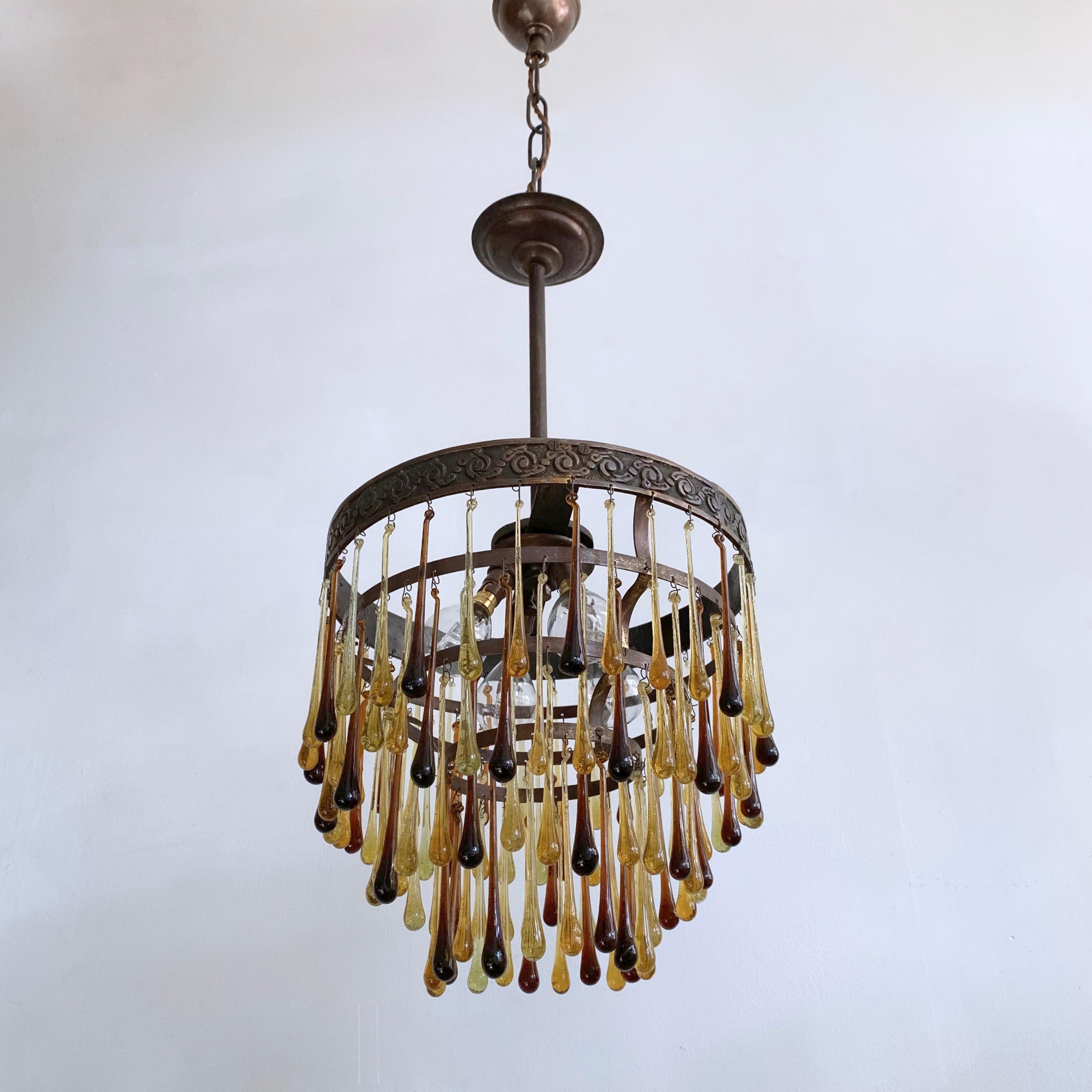 Small waterfall chandelier dressed in striking brown and amber glass teardrops. The glass droplets are a mixture of modern and vintage. The brass chandelier frame is French early 1900s and has been customized with these drops. This light would