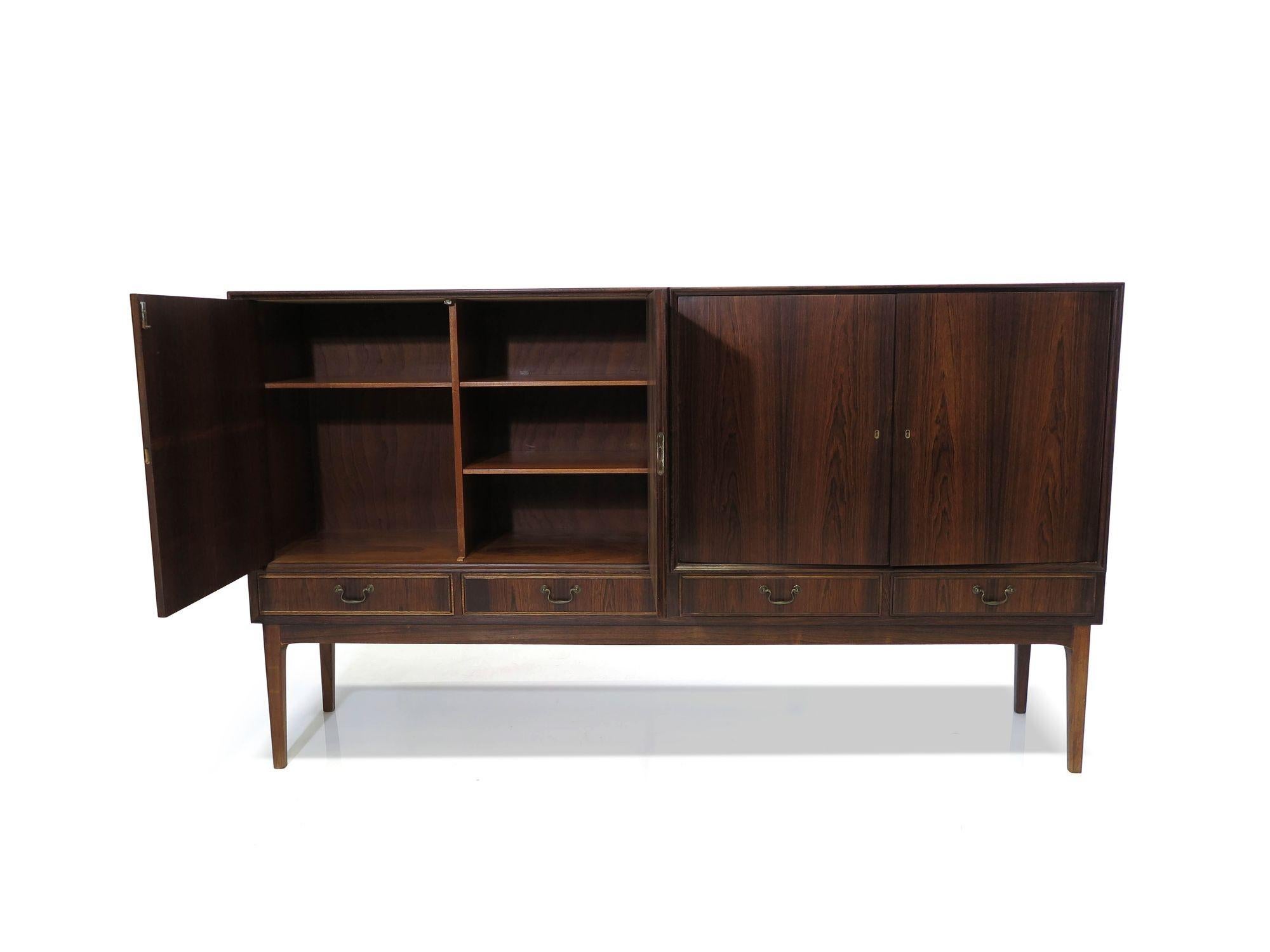 Brazilian Rosewood Sideboard attributed to Ole Wanscher, Features rich Brazilian rosewood with book-matched locking doors and drawers. The doors open to reveal an interior of mahogany with silverware drawers and adjustable shelves. The quality