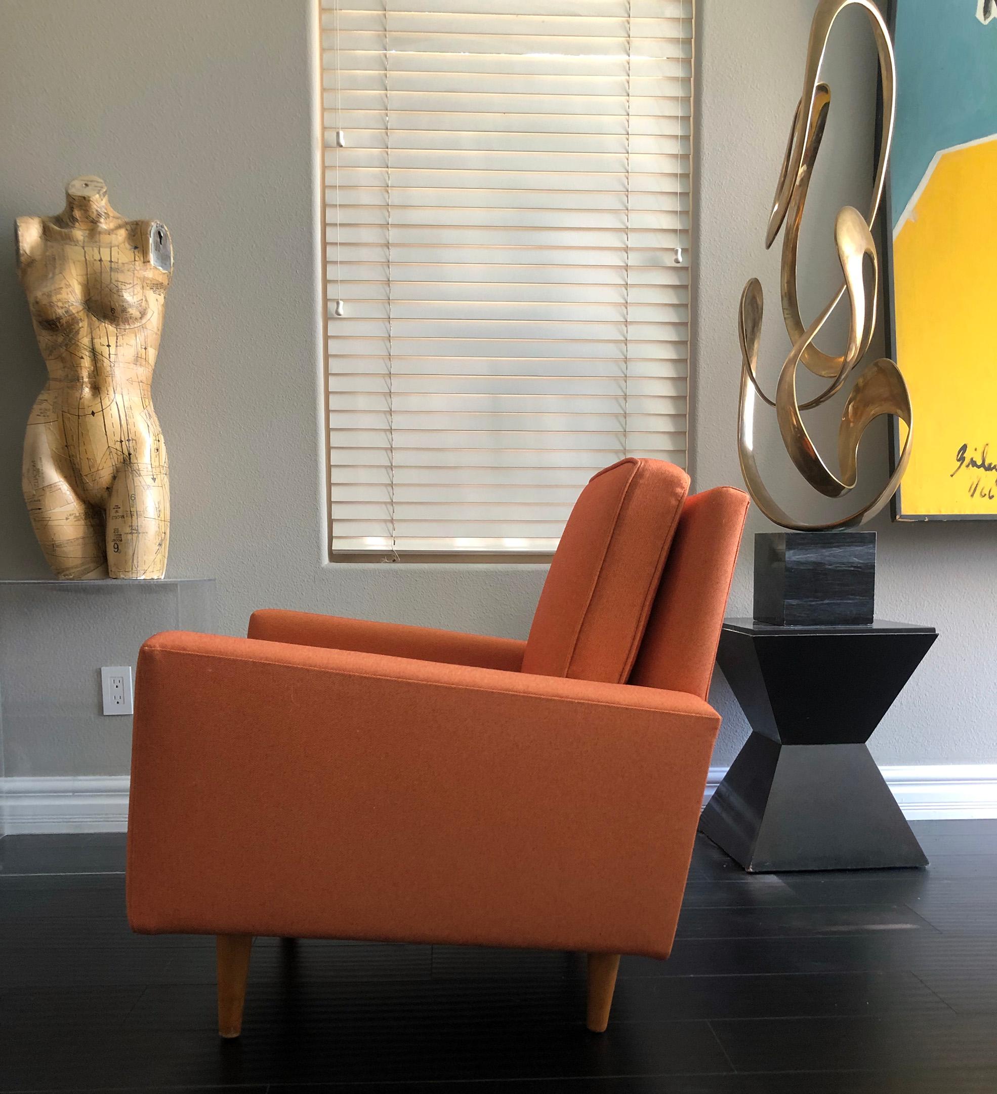 This lounge chair is truly stunning. This early Florence Knoll lounge chair features cone shaped birch legs, and fresh tangerine colored tone-on-tone period appropriate fabric. 

With its clean lines, angular body, and modern shape, this lounge