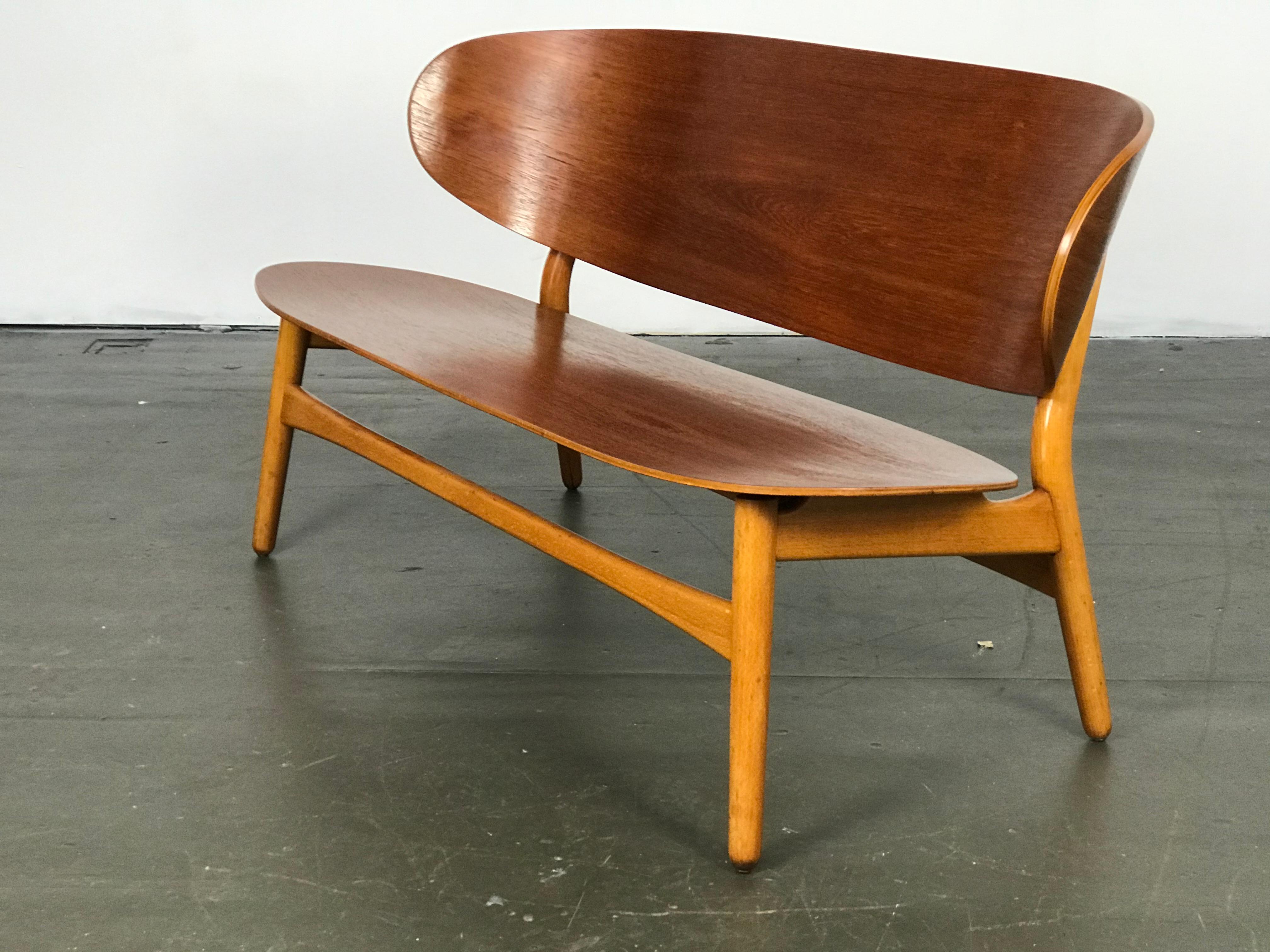 Early settee designed by Hans Wegner for Fritz Hansen in 1948. Made of teak and beech wood, this settee has been restored several years ago, yet still shows small areas of wear/age. Label remnant underneath. Early photos show these sometimes having